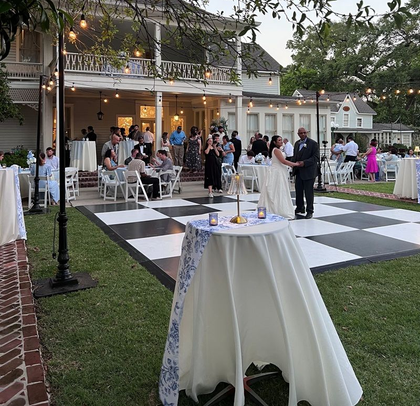 An outdoor wedding ceremony setup featuring white drapes, floral arrangements, chandeliers, and rows of white chairs. An outdoor wedding ceremony setup featuring white drapes, floral arrangements, chandeliers, and rows of white chairs.