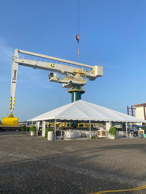 Large crane lifting equipment over a white tent at an industrial site under a blue sky. Large crane lifting equipment over a white tent at an industrial site under a blue sky.
