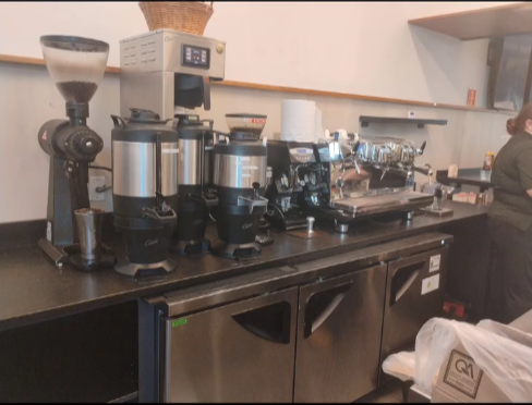 A woman stands behind a counter in a coffee shop