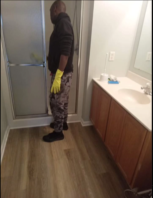 A man wearing yellow gloves is standing in a bathroom