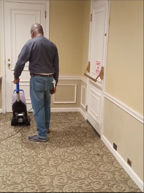 A man is using a vacuum cleaner to clean a hallway