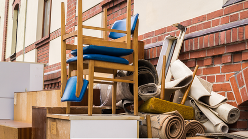 A pile of furniture and carpets is sitting in front of a brick building.