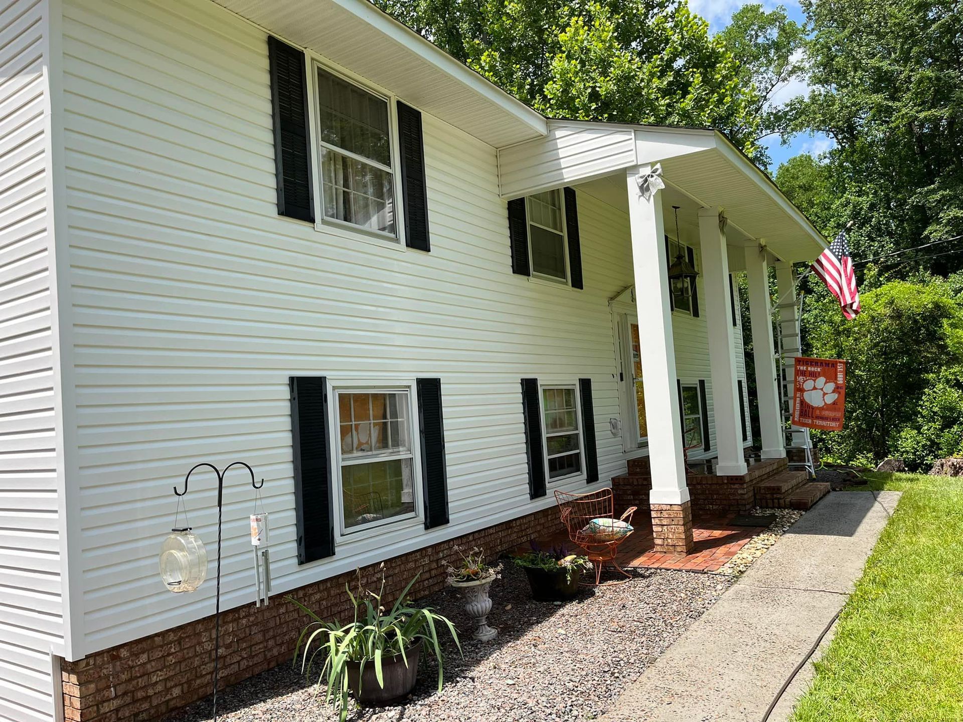 A white house with black shutters and an american flag