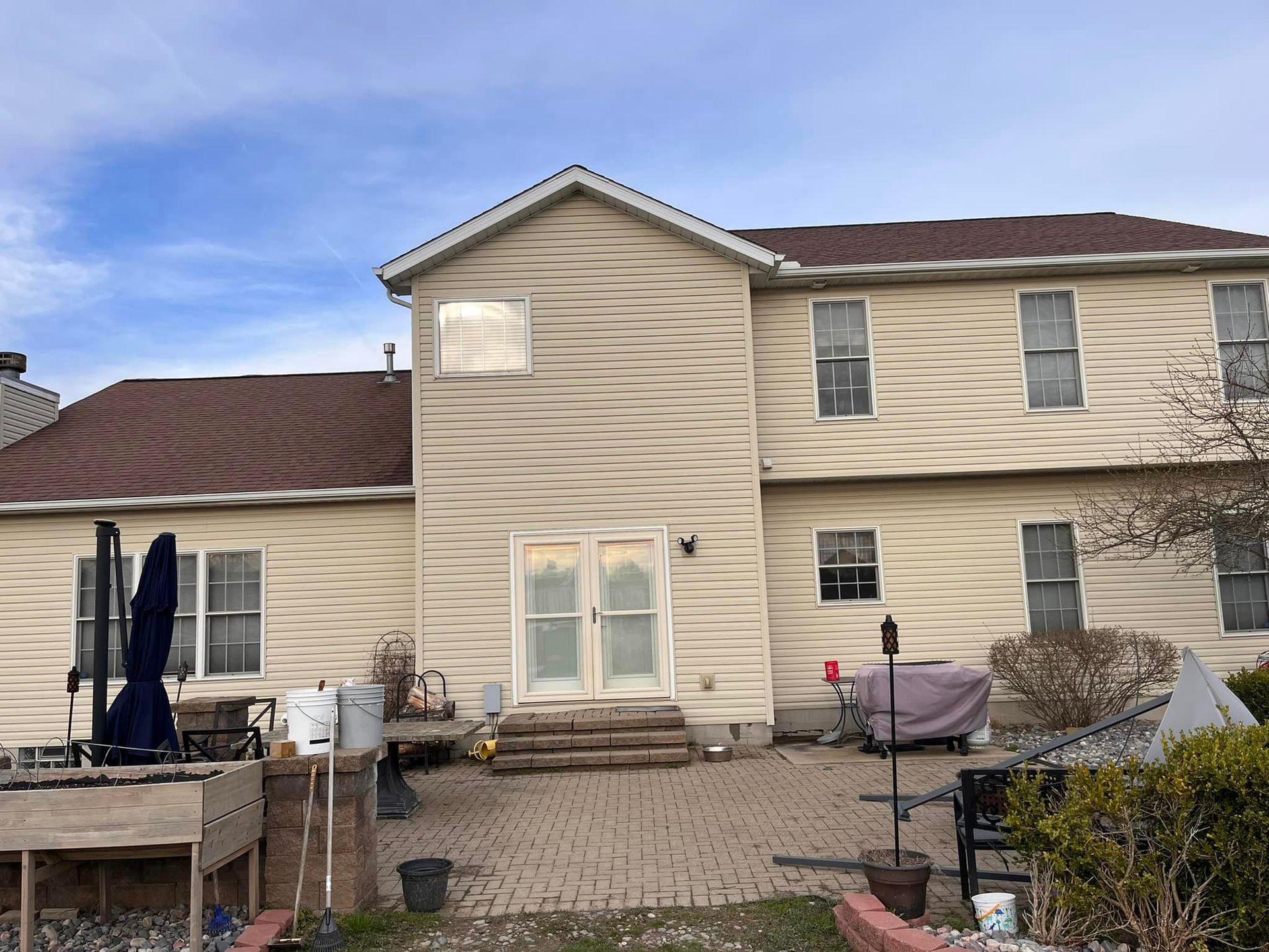 A large house with a red roof and a patio in front of it.