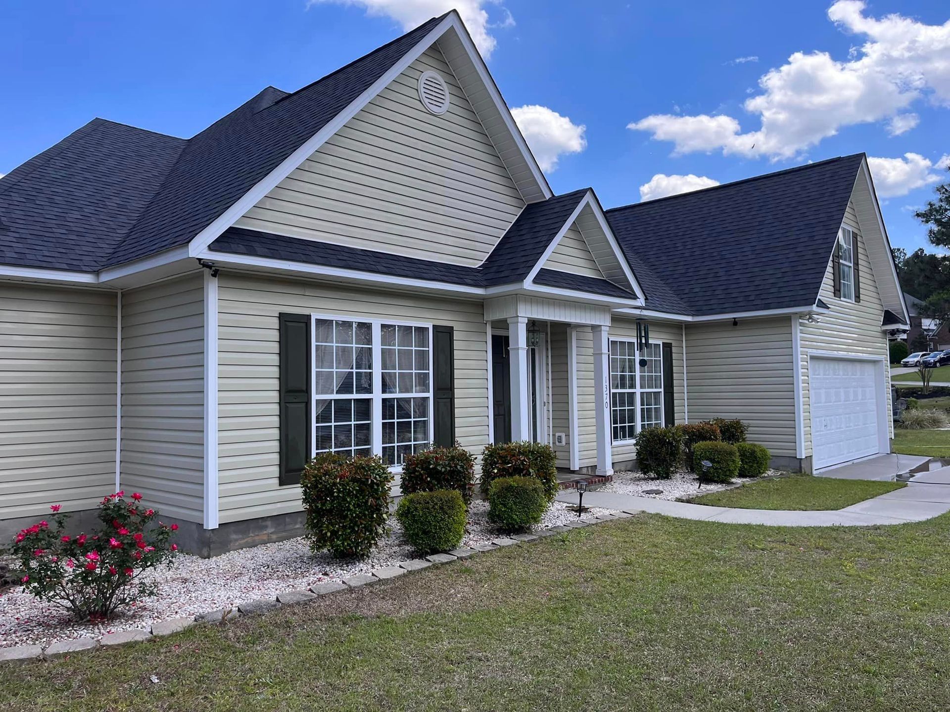 A large house with a black roof and white siding