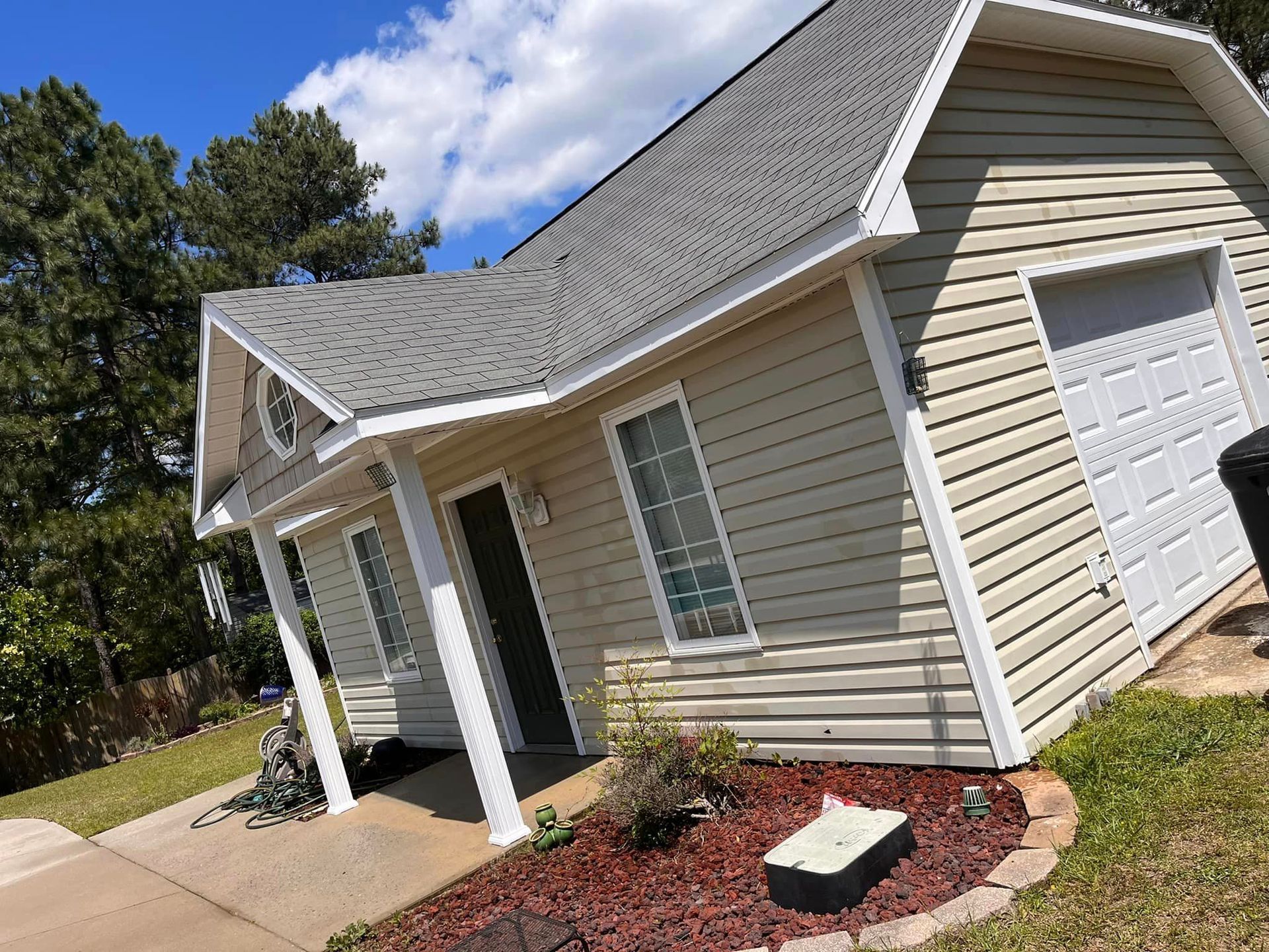 A small house with a garage and a porch on a sunny day.