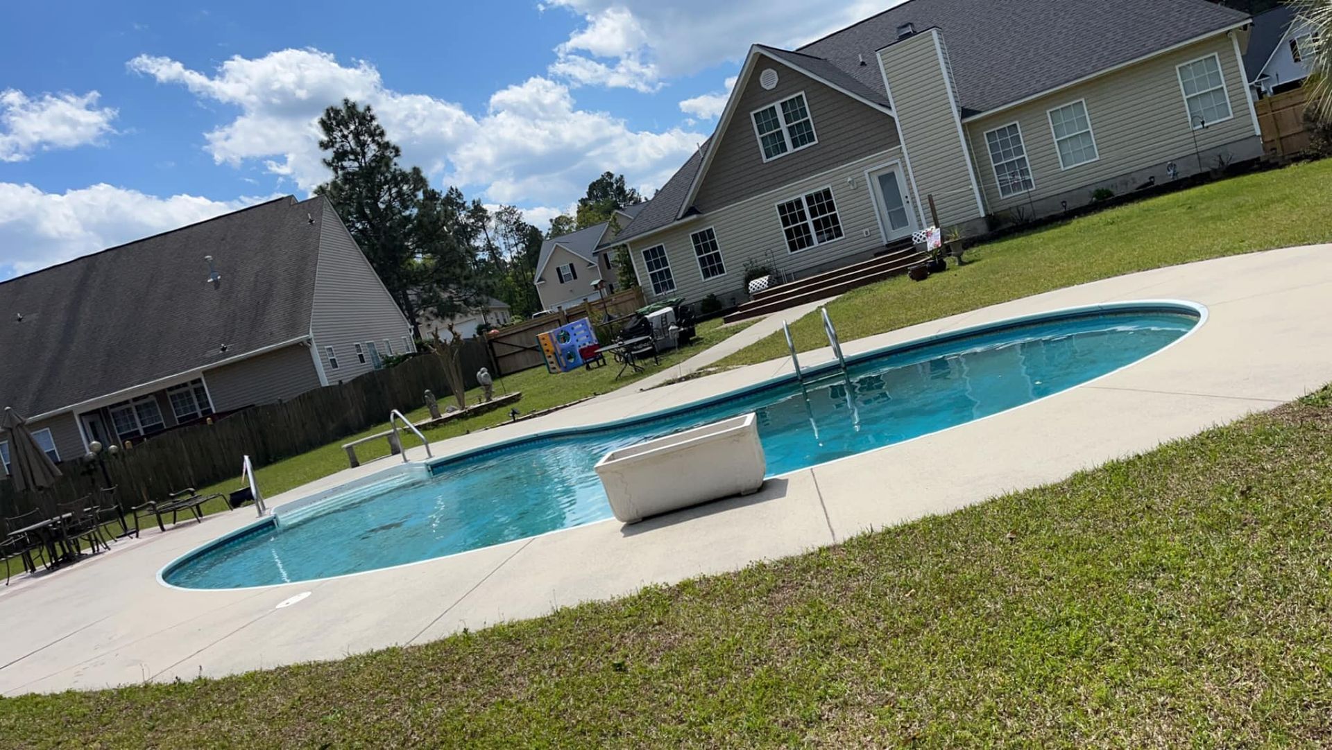 A large swimming pool is in the backyard of a house.
