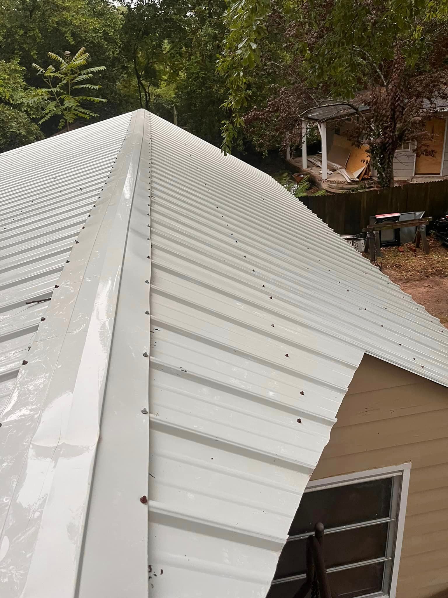A white metal roof is being installed on a house.