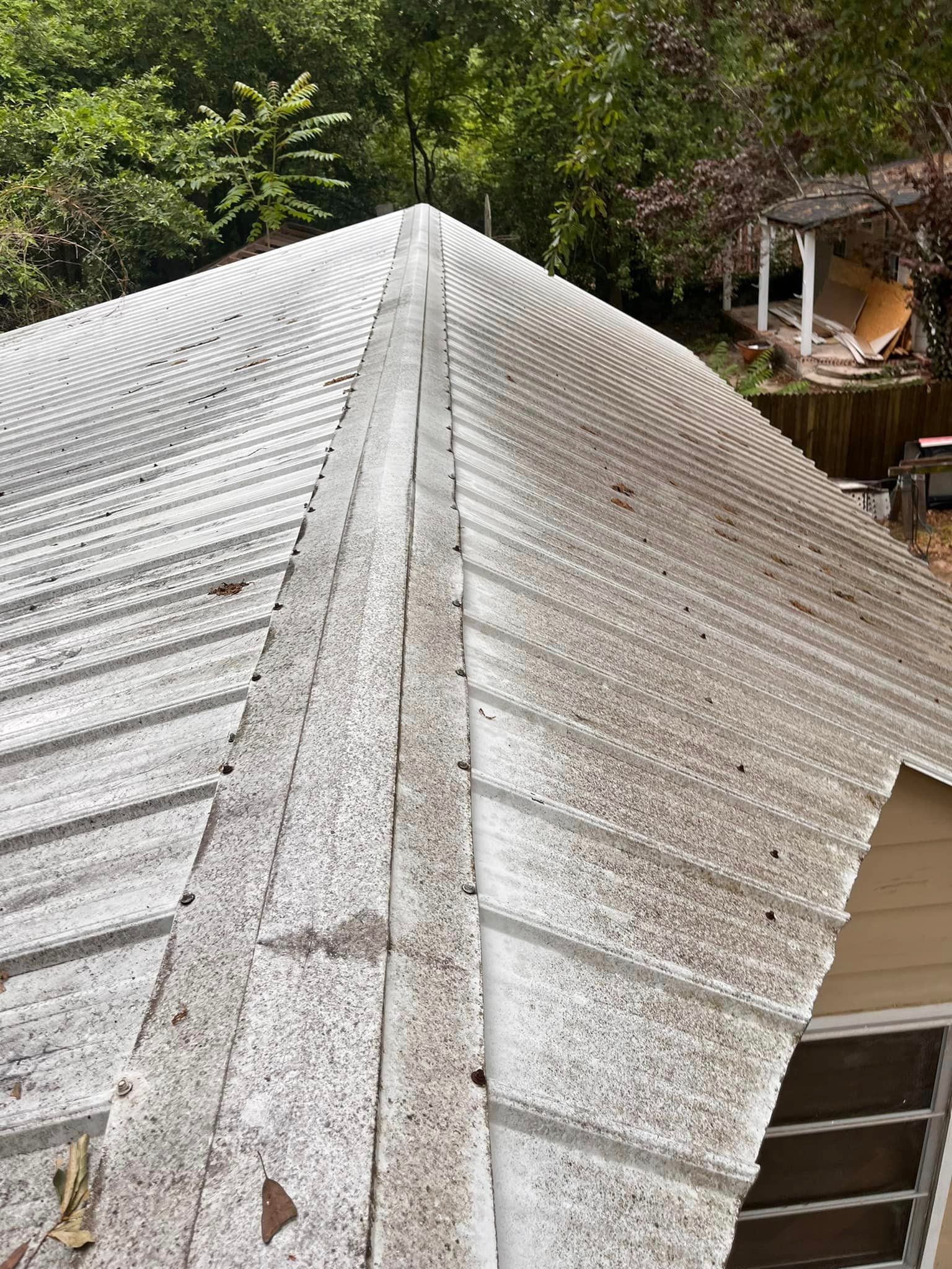 The roof of a house is covered in leaves and dirt.