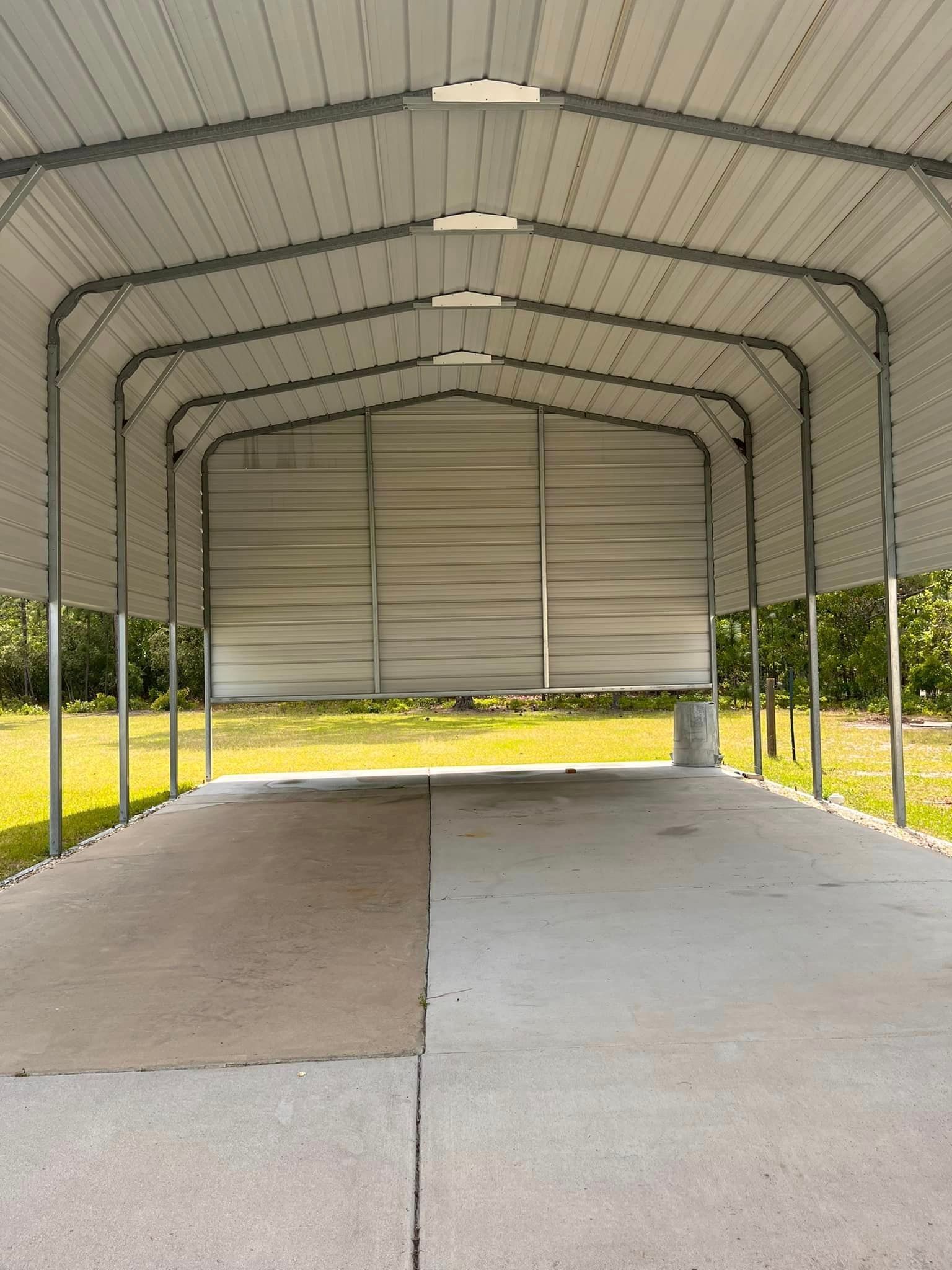 A carport with a concrete floor and a metal roof.