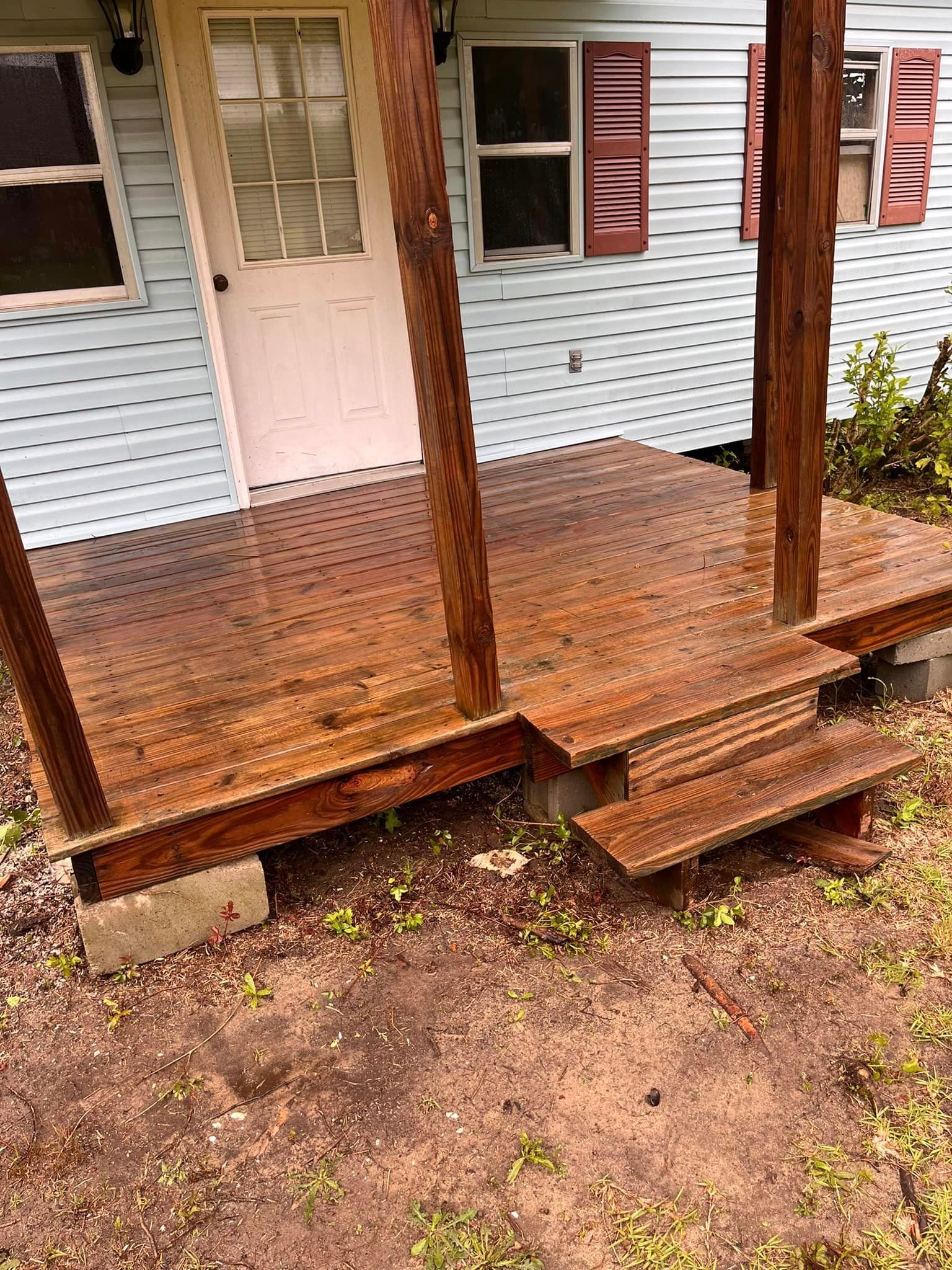 A wooden porch with stairs is in front of a house.