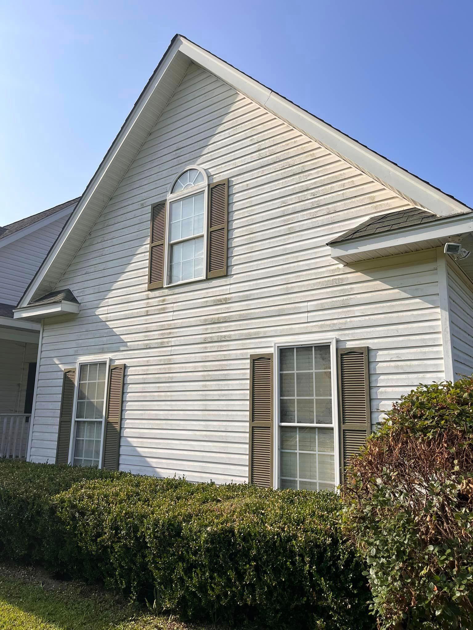 A white house with brown shutters and a blue sky in the background.