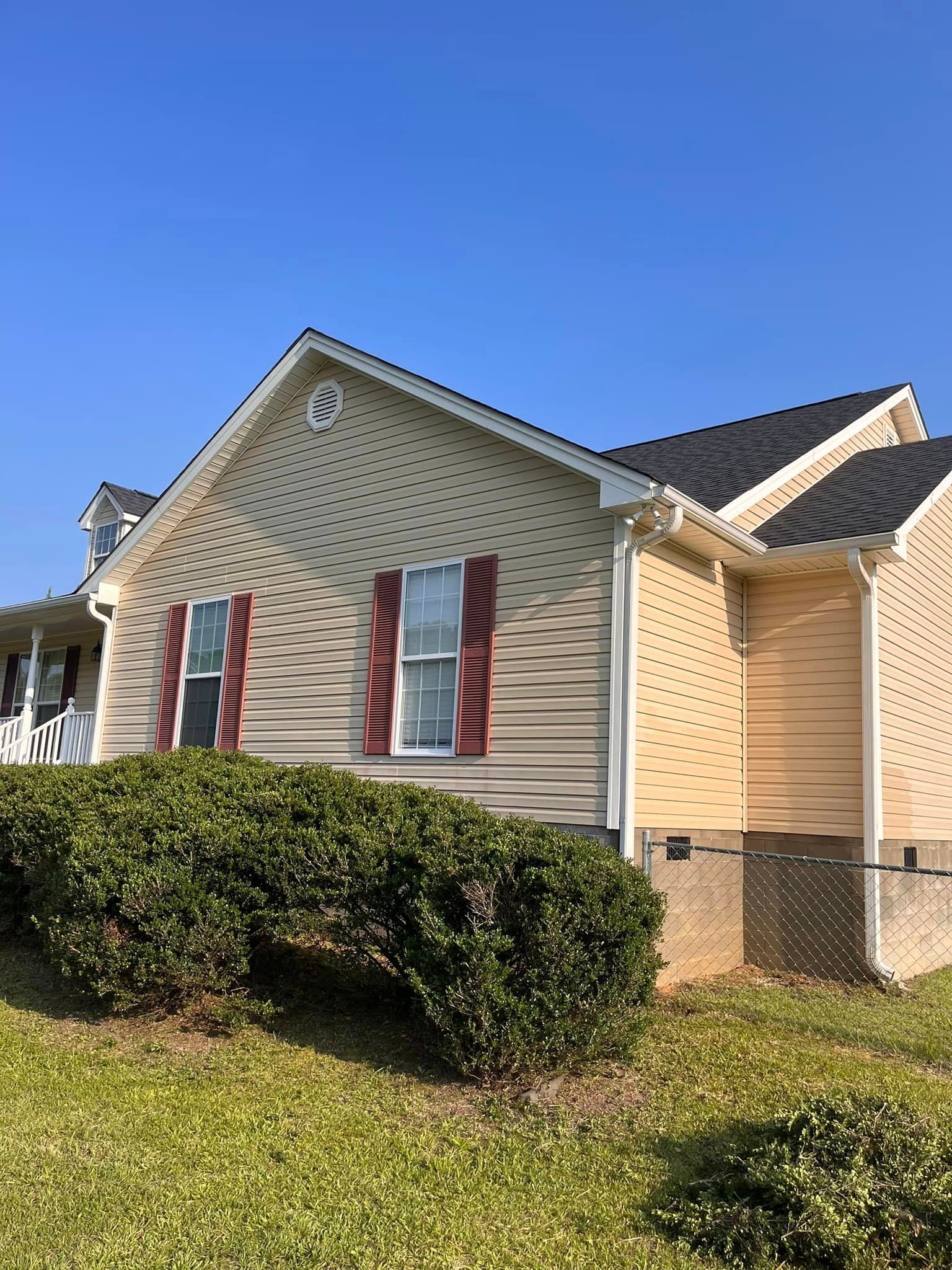 A house with a fence in front of it and a blue sky in the background.