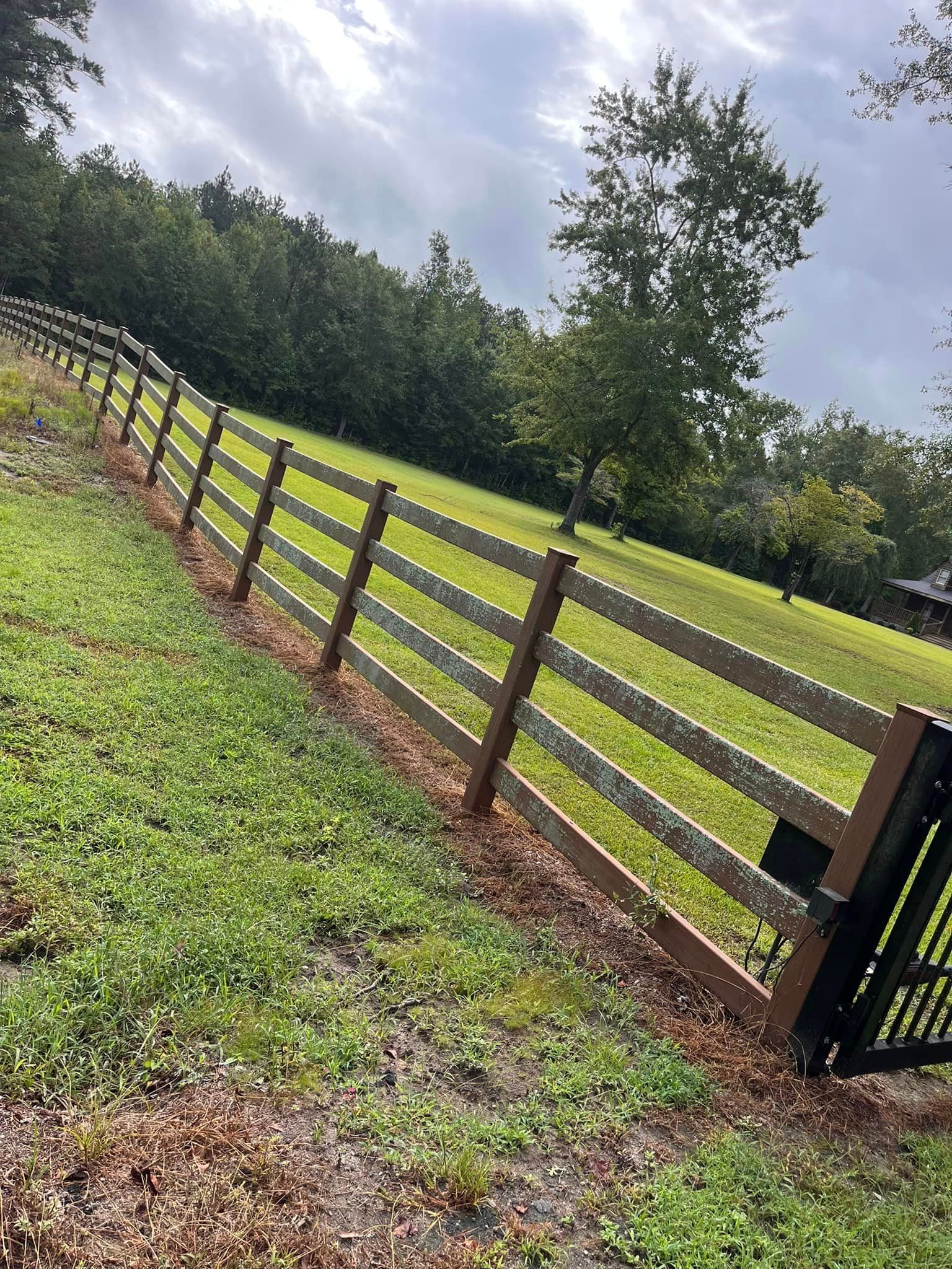A wooden fence surrounds a lush green field.