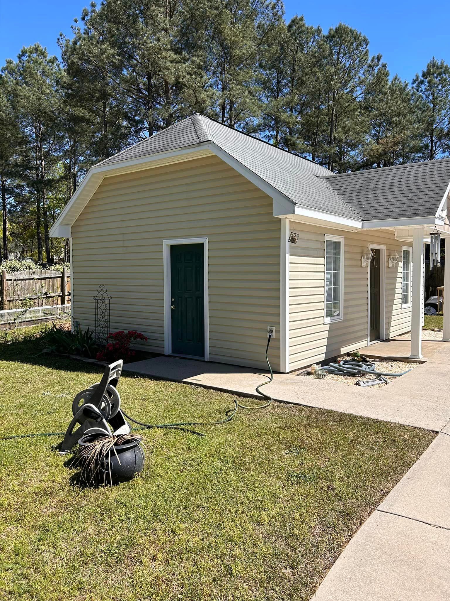 A small house with a green door is sitting in the middle of a lush green field.