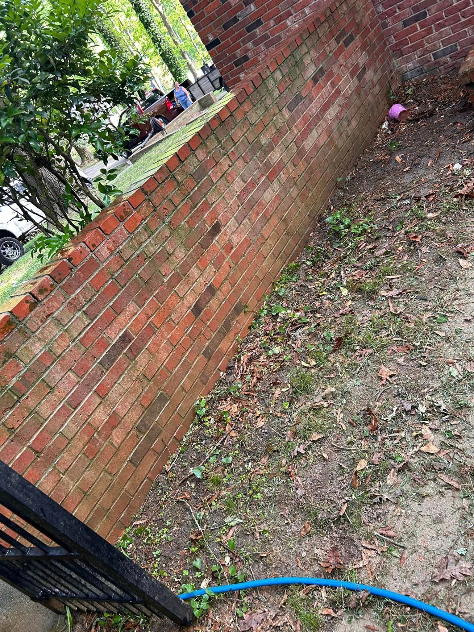 A brick wall with a blue hose in front of it.