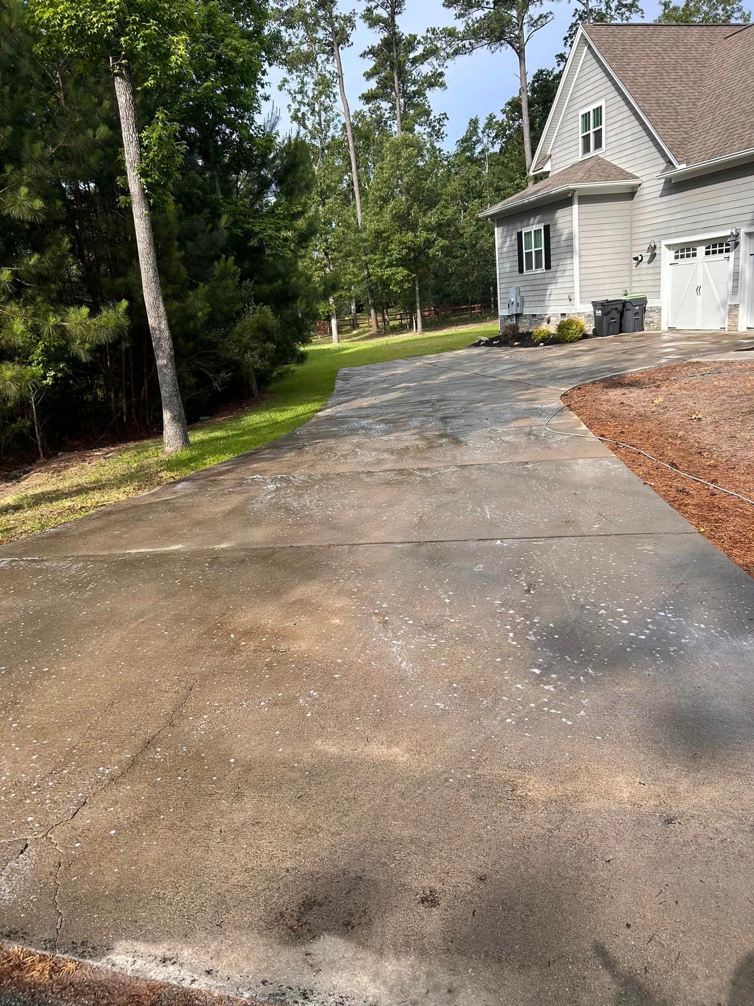 A dirty driveway leading to a house with trees in the background.