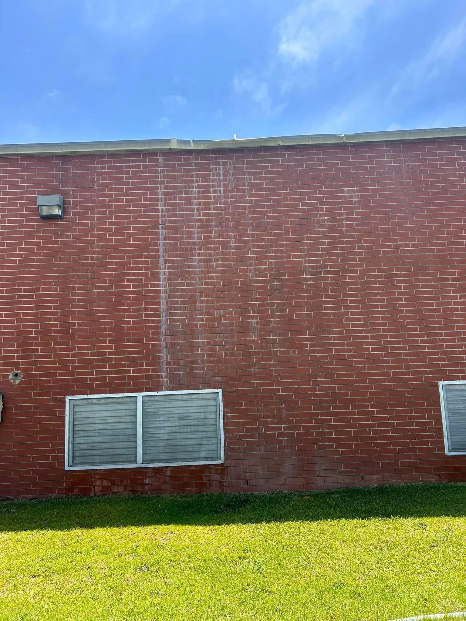A red brick building with two windows and a blue sky in the background.