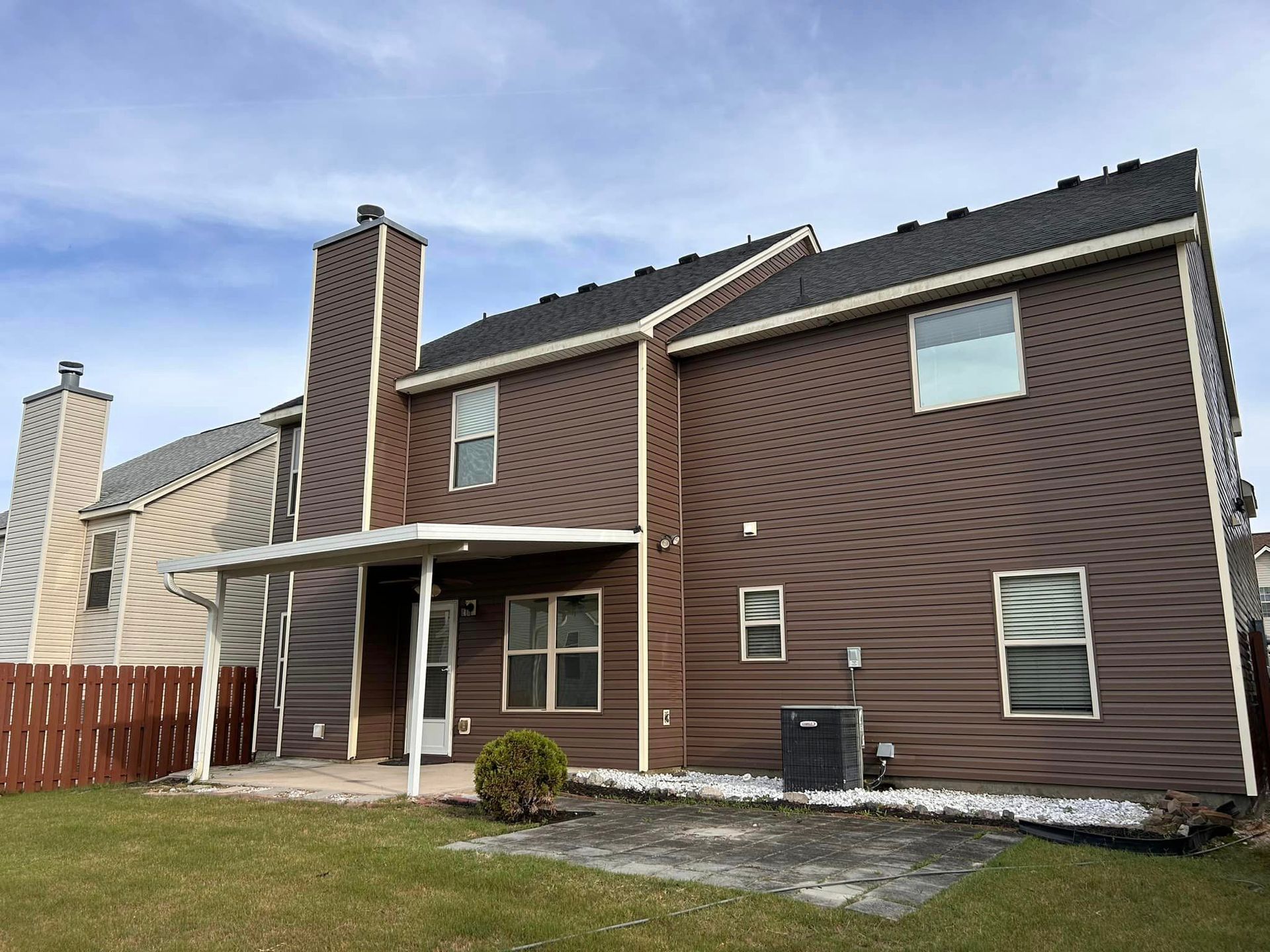 The back of a brown house with a porch and a chimney