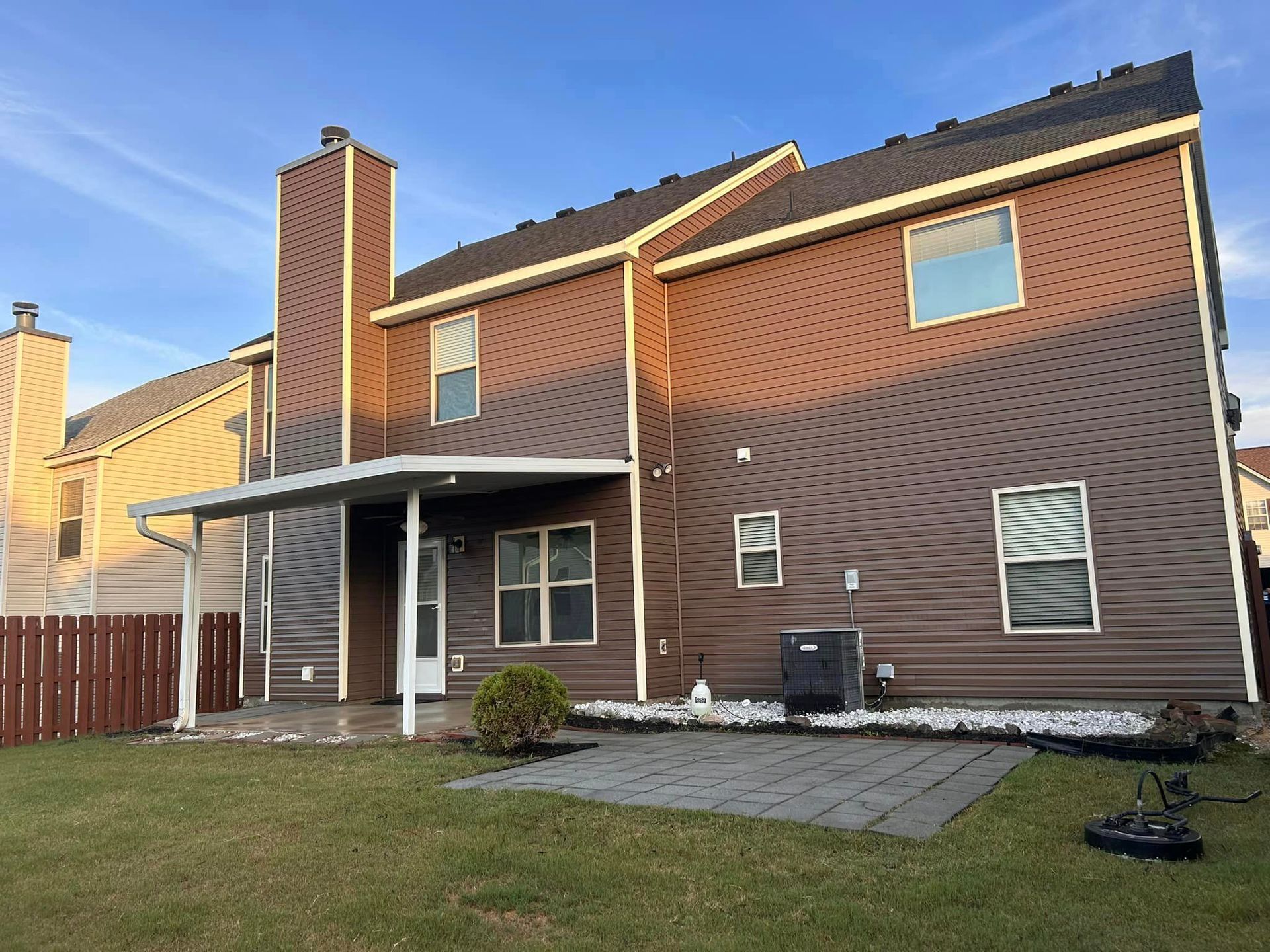 The back of a house with a covered porch and a chimney.