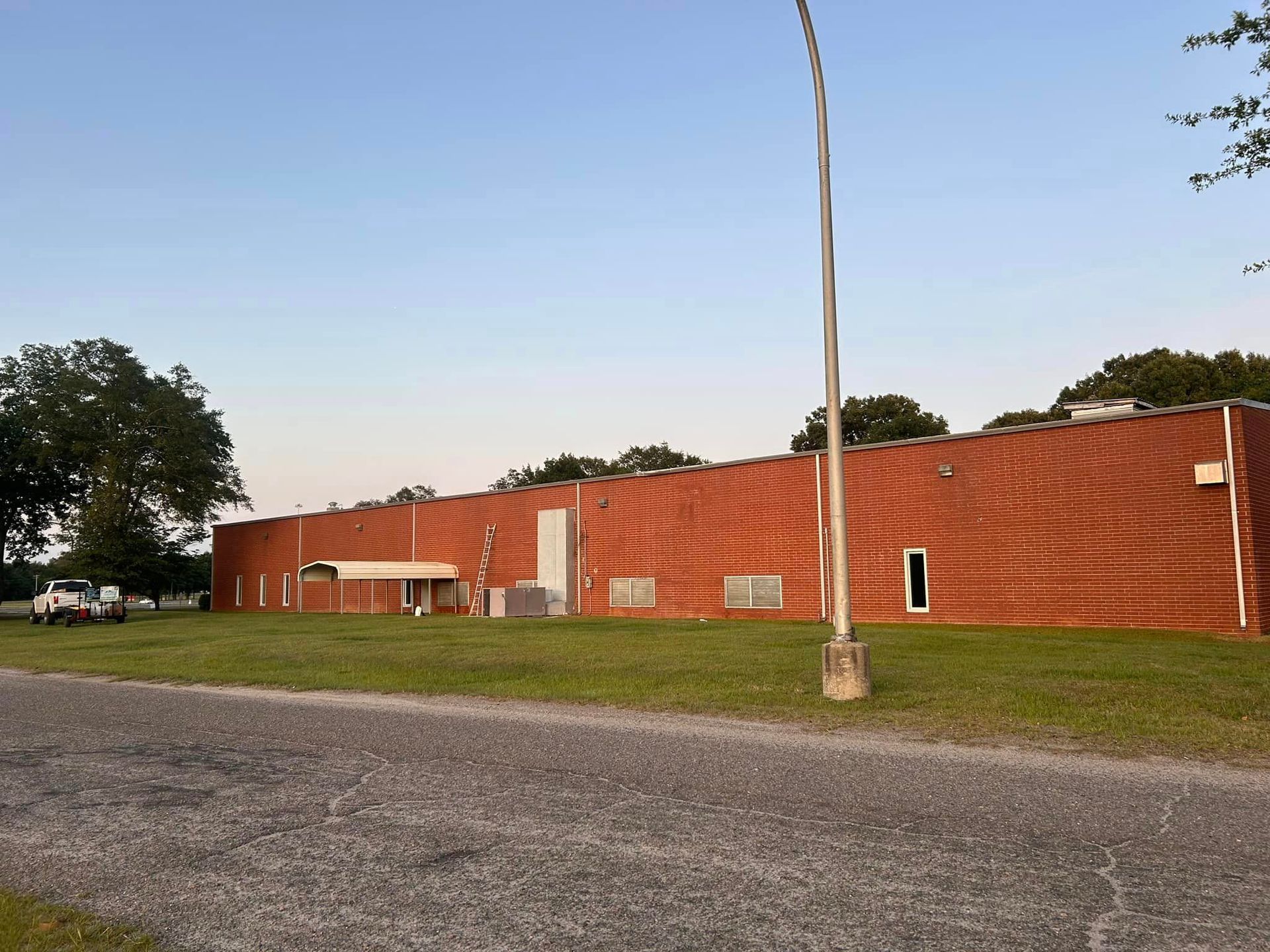 A large red brick building sits in the middle of a grassy field