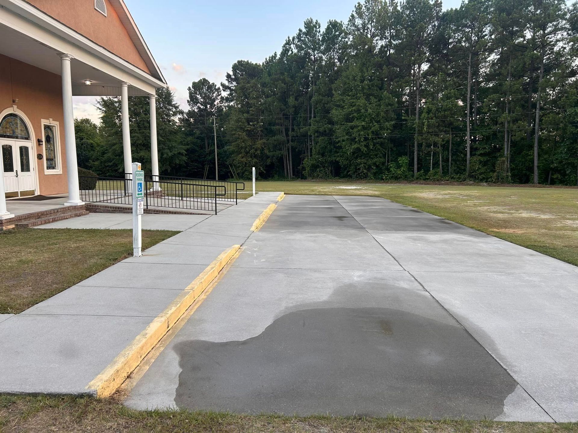A concrete walkway leading to a building with trees in the background