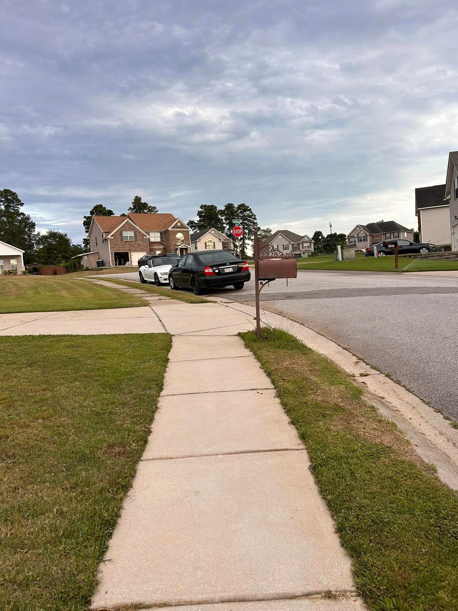 A car is parked on the side of the road next to a mailbox.