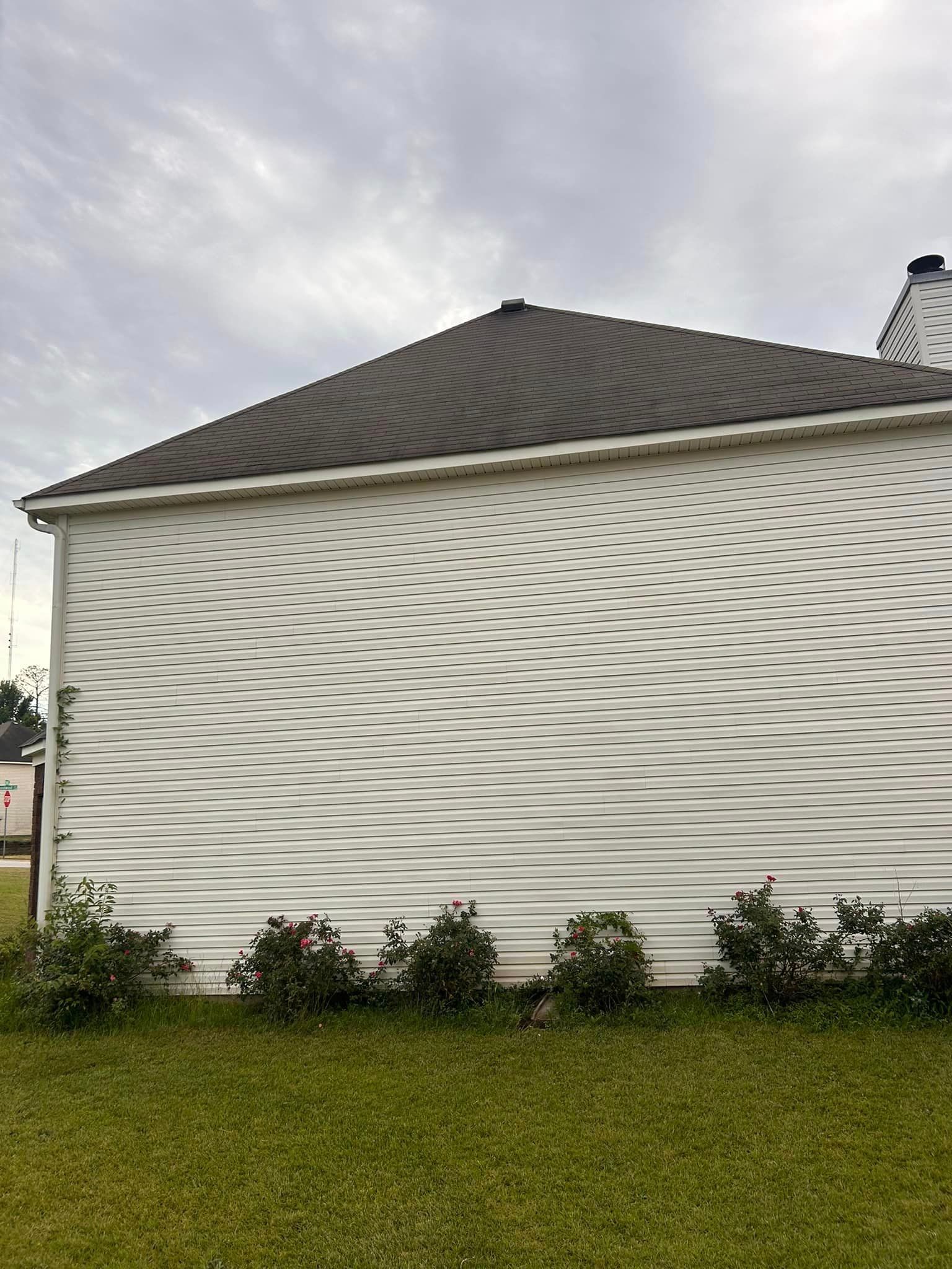 A white house with a black roof is sitting on top of a lush green lawn.