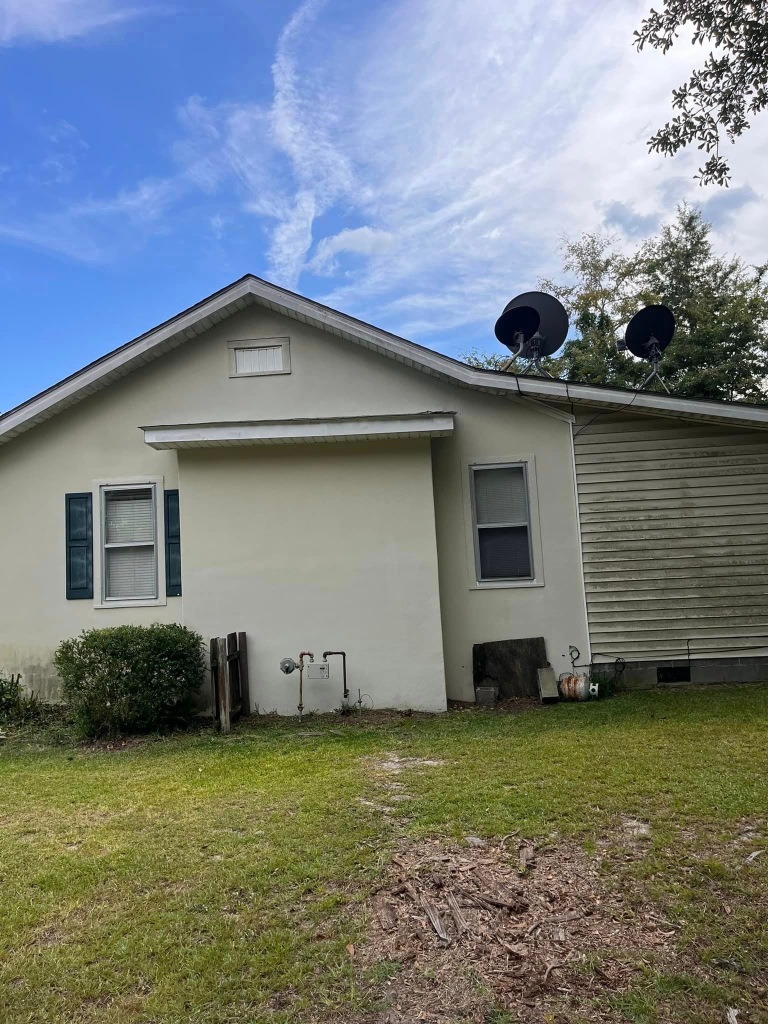 A white house with satellite dishes on the roof and a blue sky in the background.