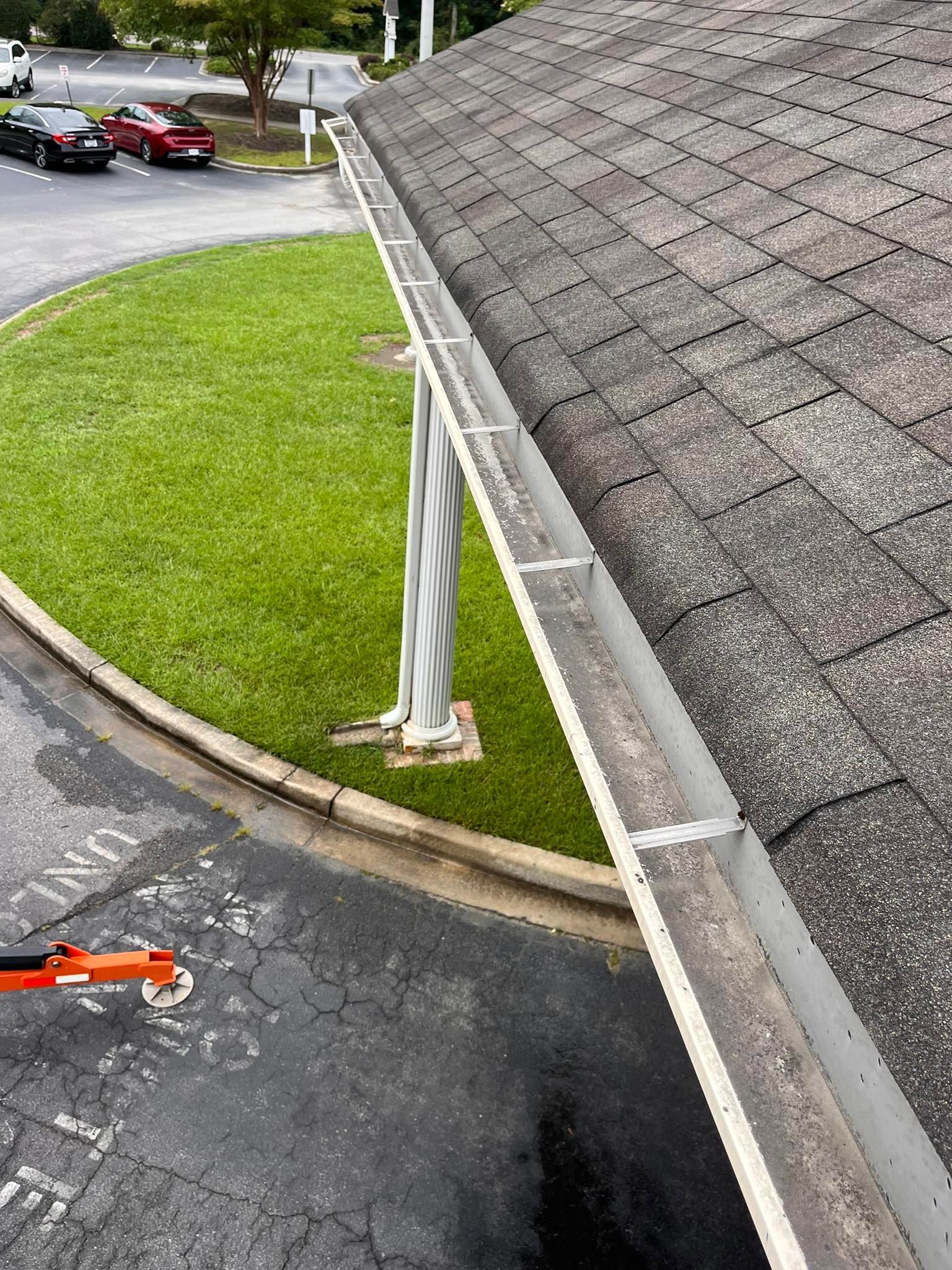 A gutter is sitting on top of a roof next to a parking lot.