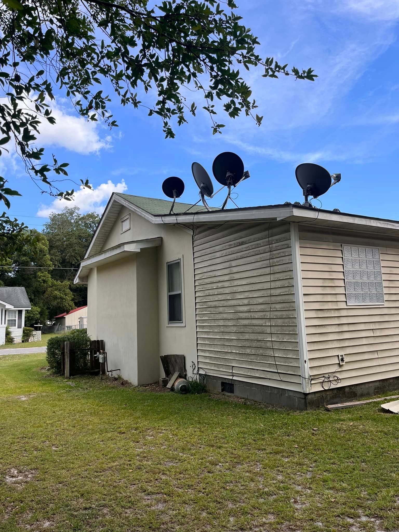 A small white house with satellite dishes on the roof