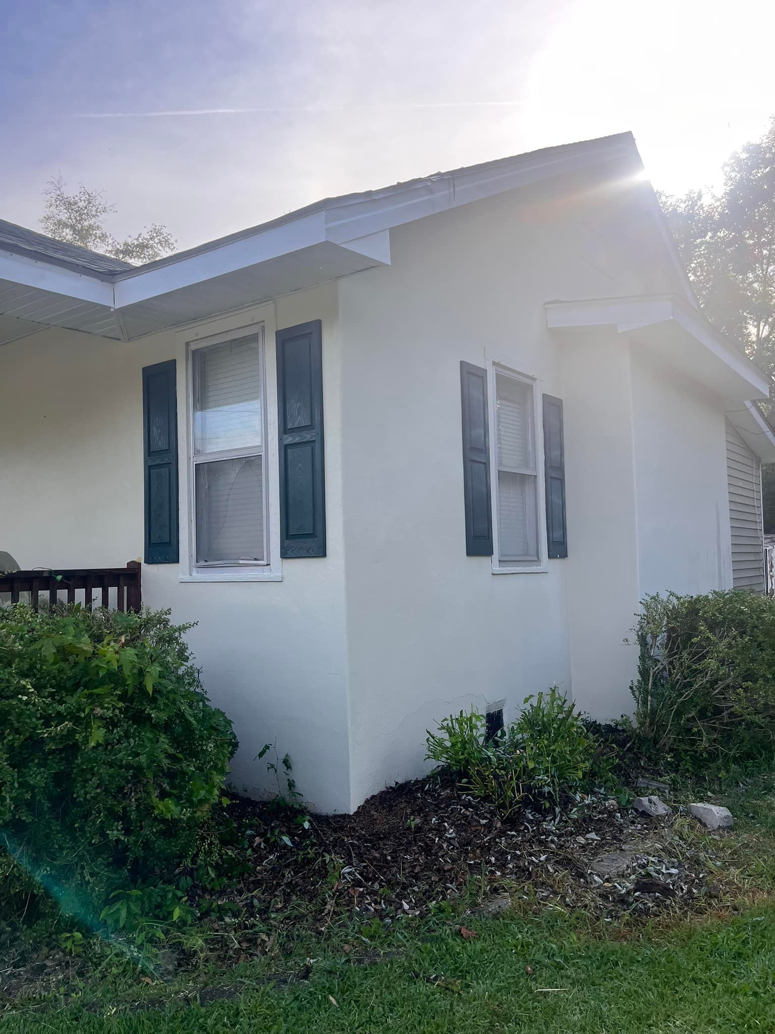 A white house with black shutters and a blue sky in the background.