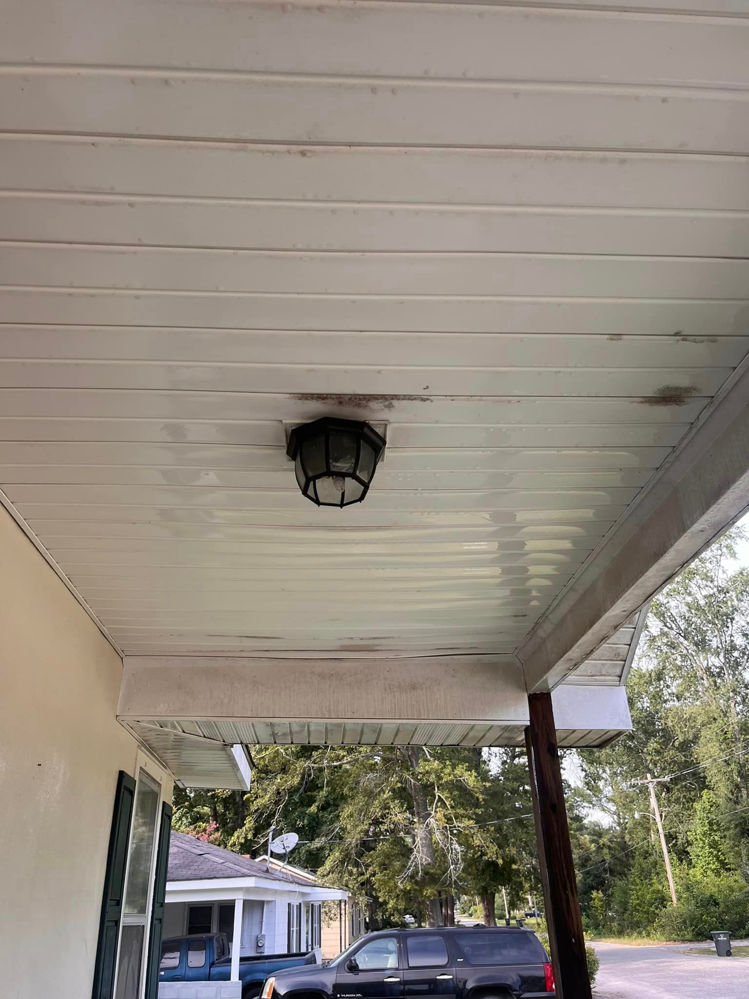 There is a light on the ceiling of the porch of a house.