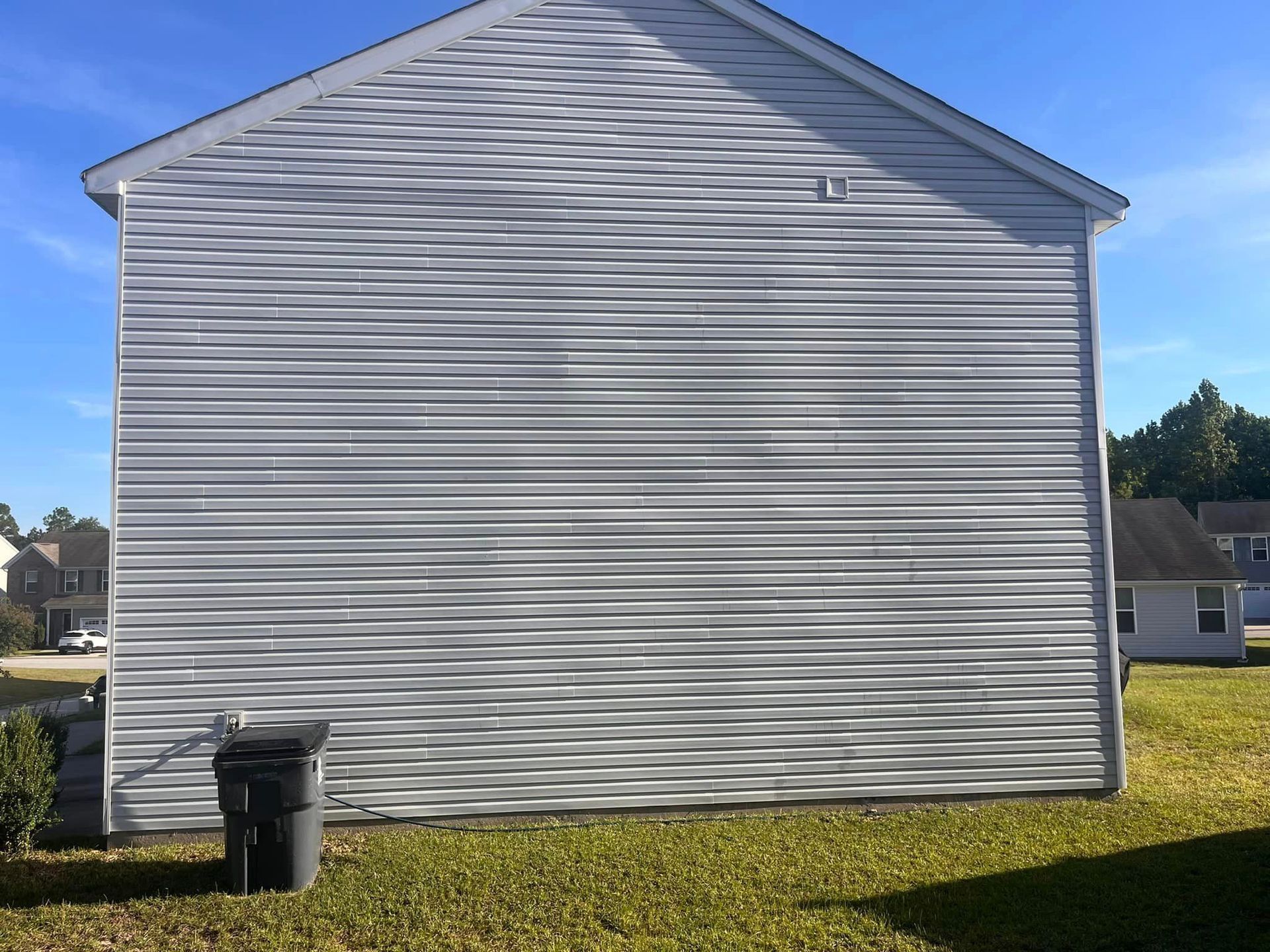 A large white house with a black trash can in front of it