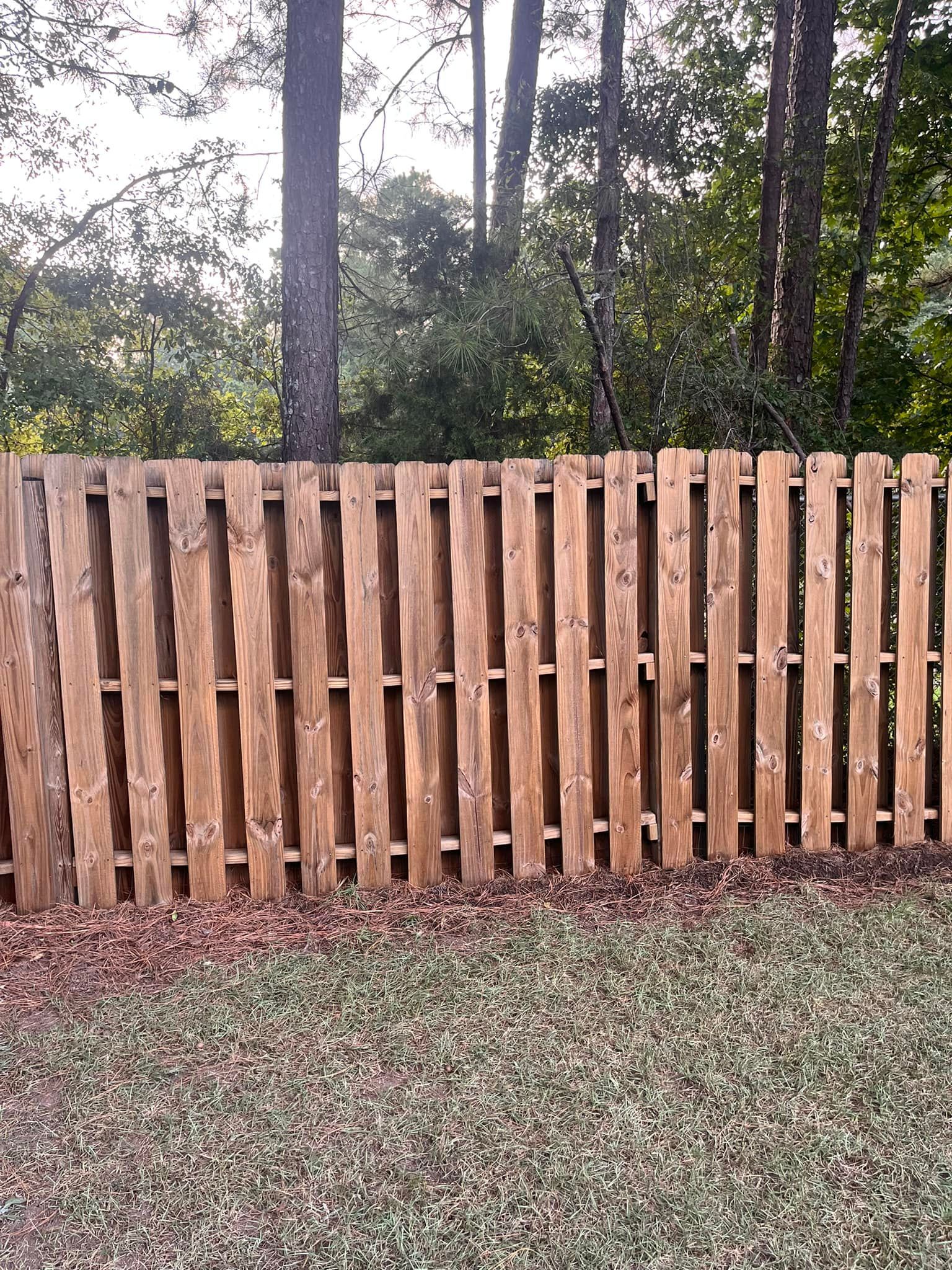 A wooden fence is sitting in the middle of a lush green field.