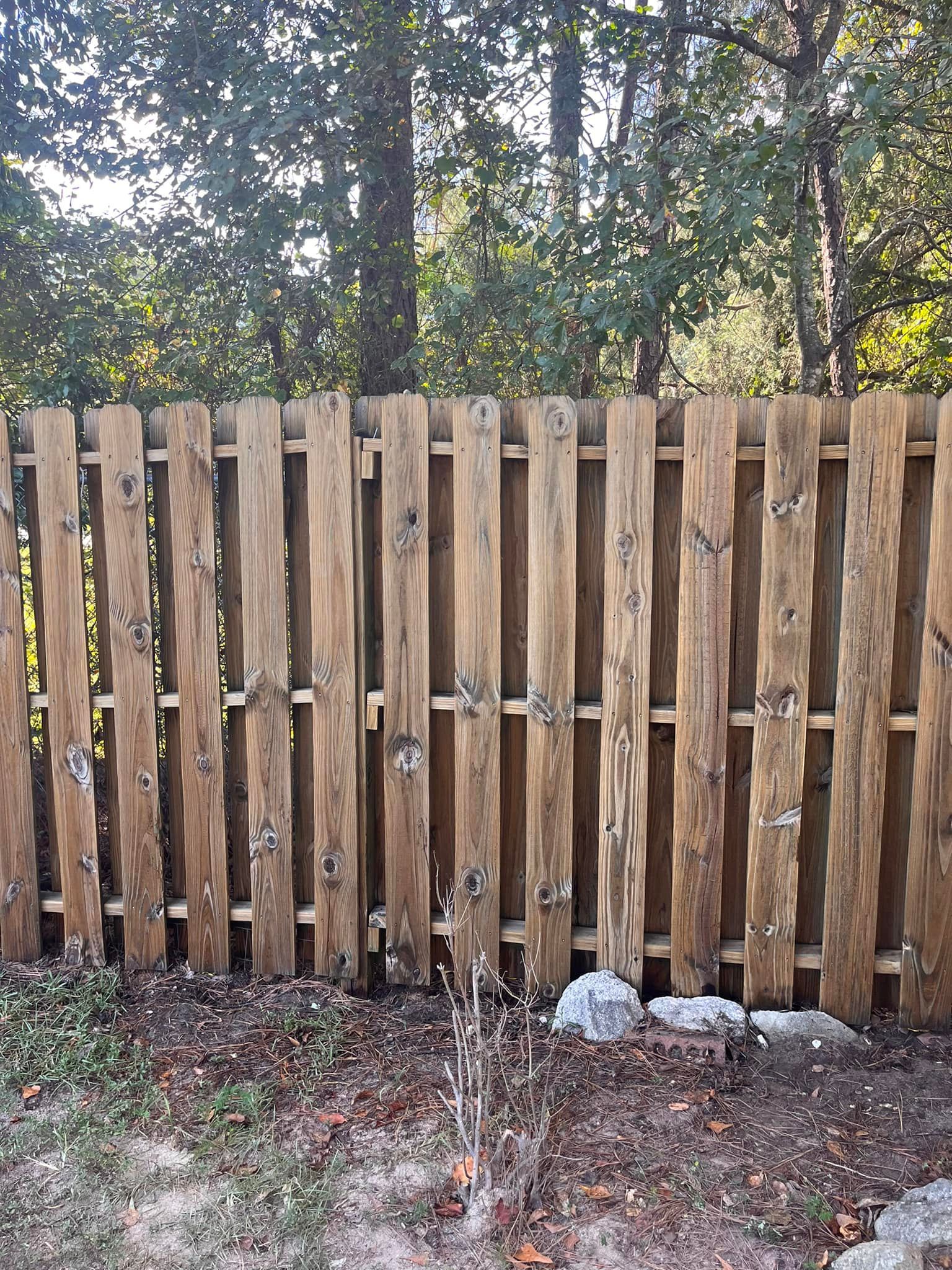 A wooden fence is in the middle of a forest.