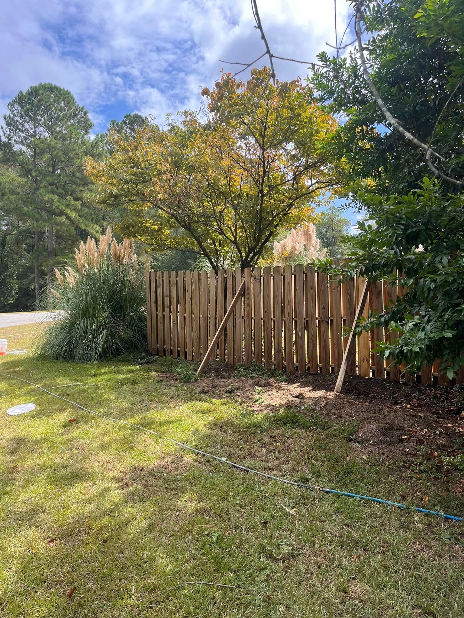 A wooden fence is sitting in the middle of a lush green yard.