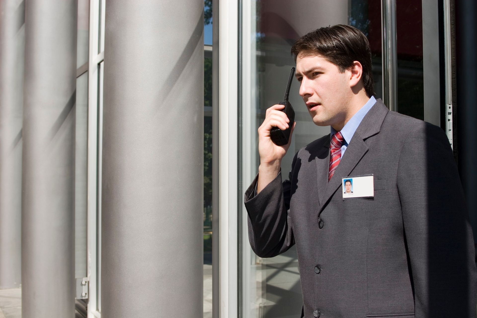 A man in a suit and tie is talking on a walkie talkie.