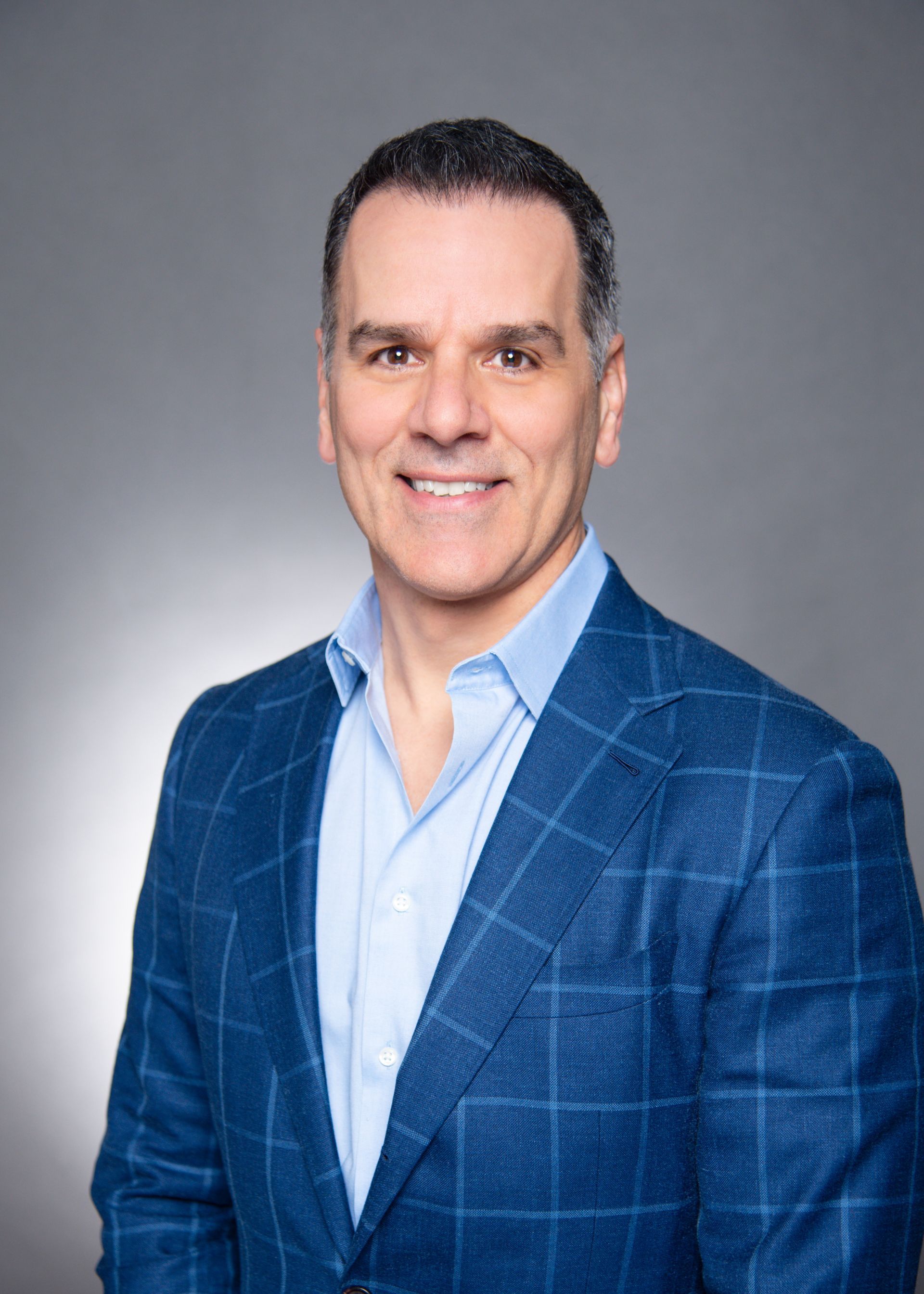 A man in a blue suit and blue shirt is smiling for the camera.