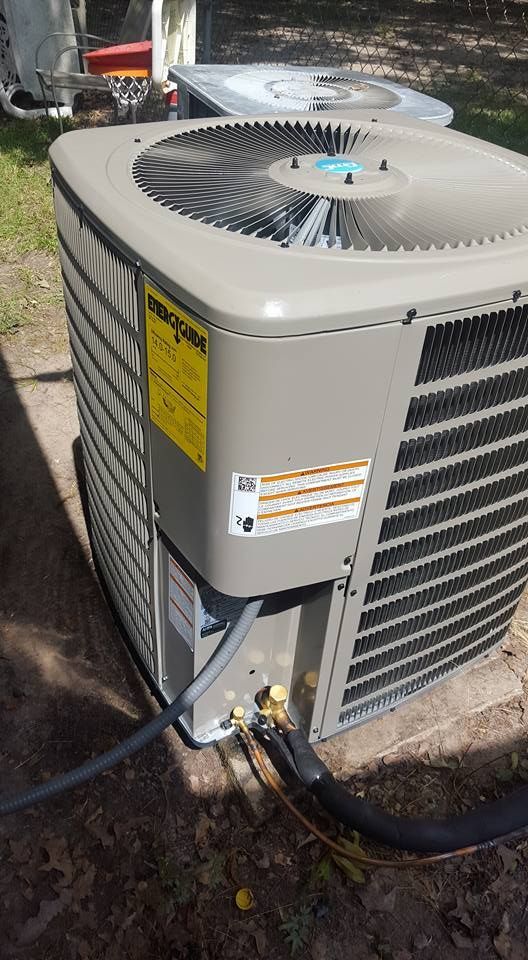 An air conditioning unit with a fan on top and yellow energy efficiency sticker, outdoors.