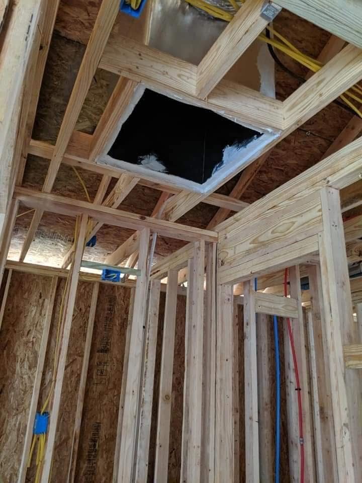 Framed wooden walls and ceiling; a dark square vent is centered in the ceiling.