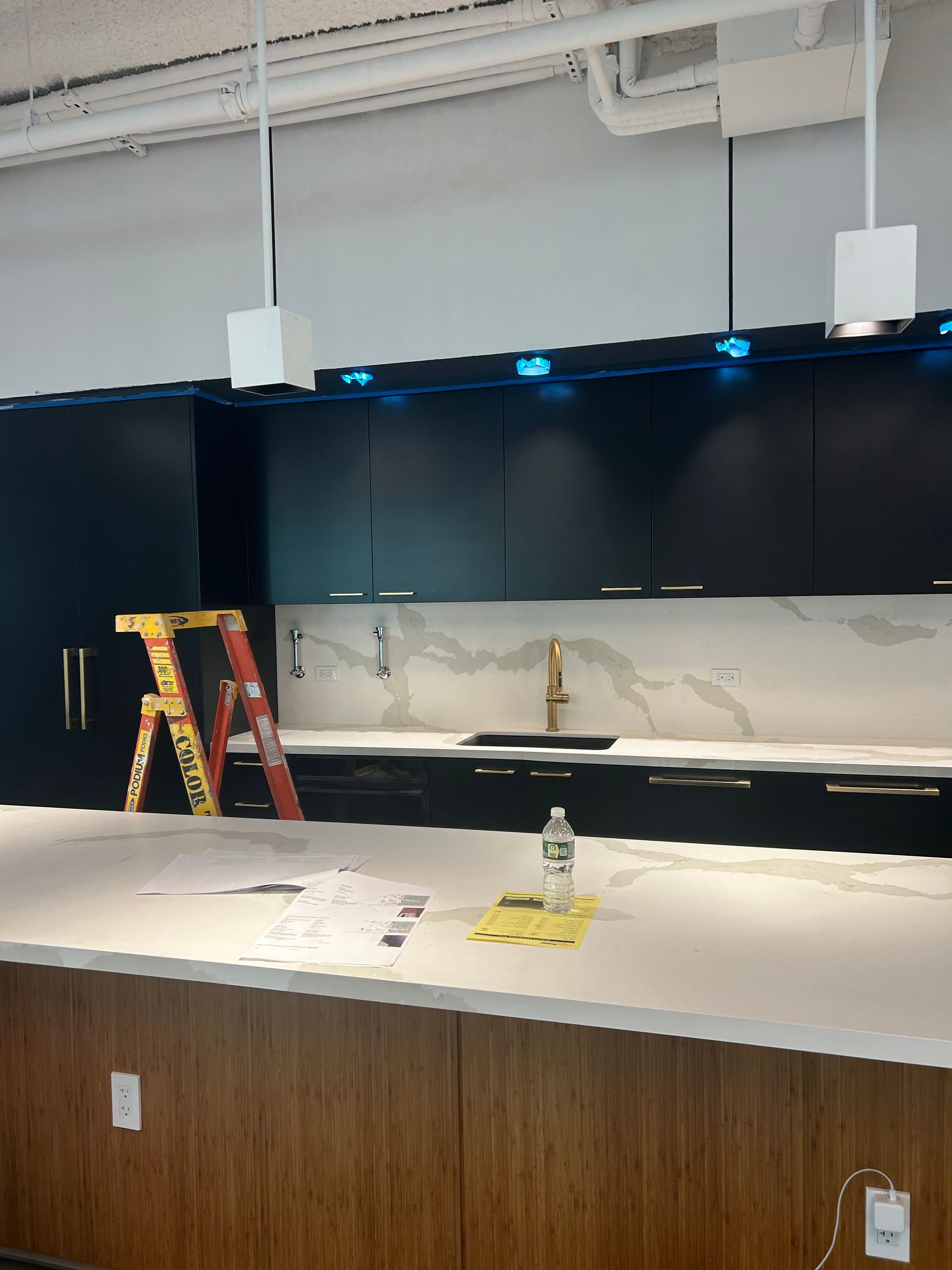 A kitchen with a ladder and a bottle of water on the counter