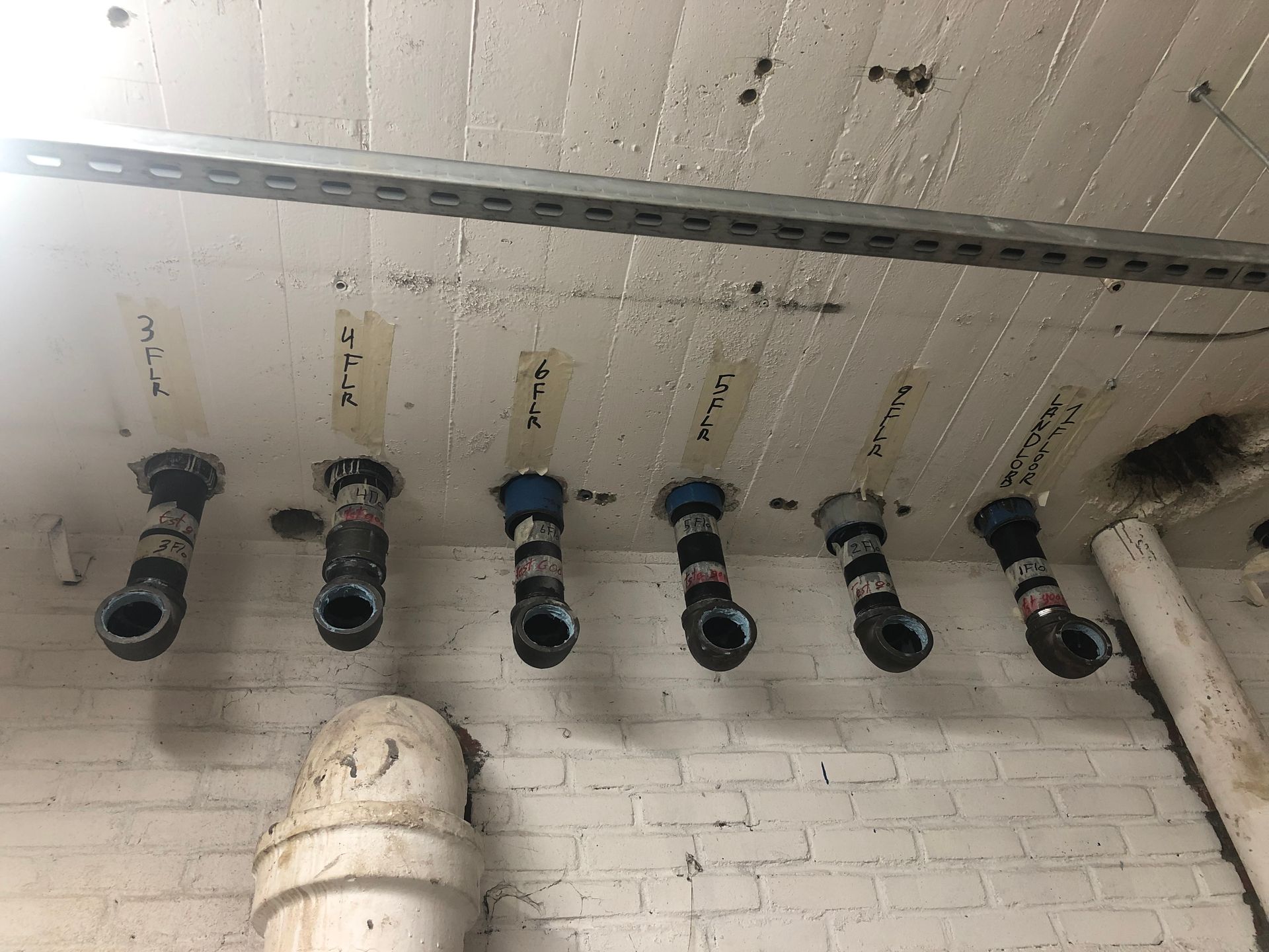 A bunch of pipes are hanging from the ceiling of a building.