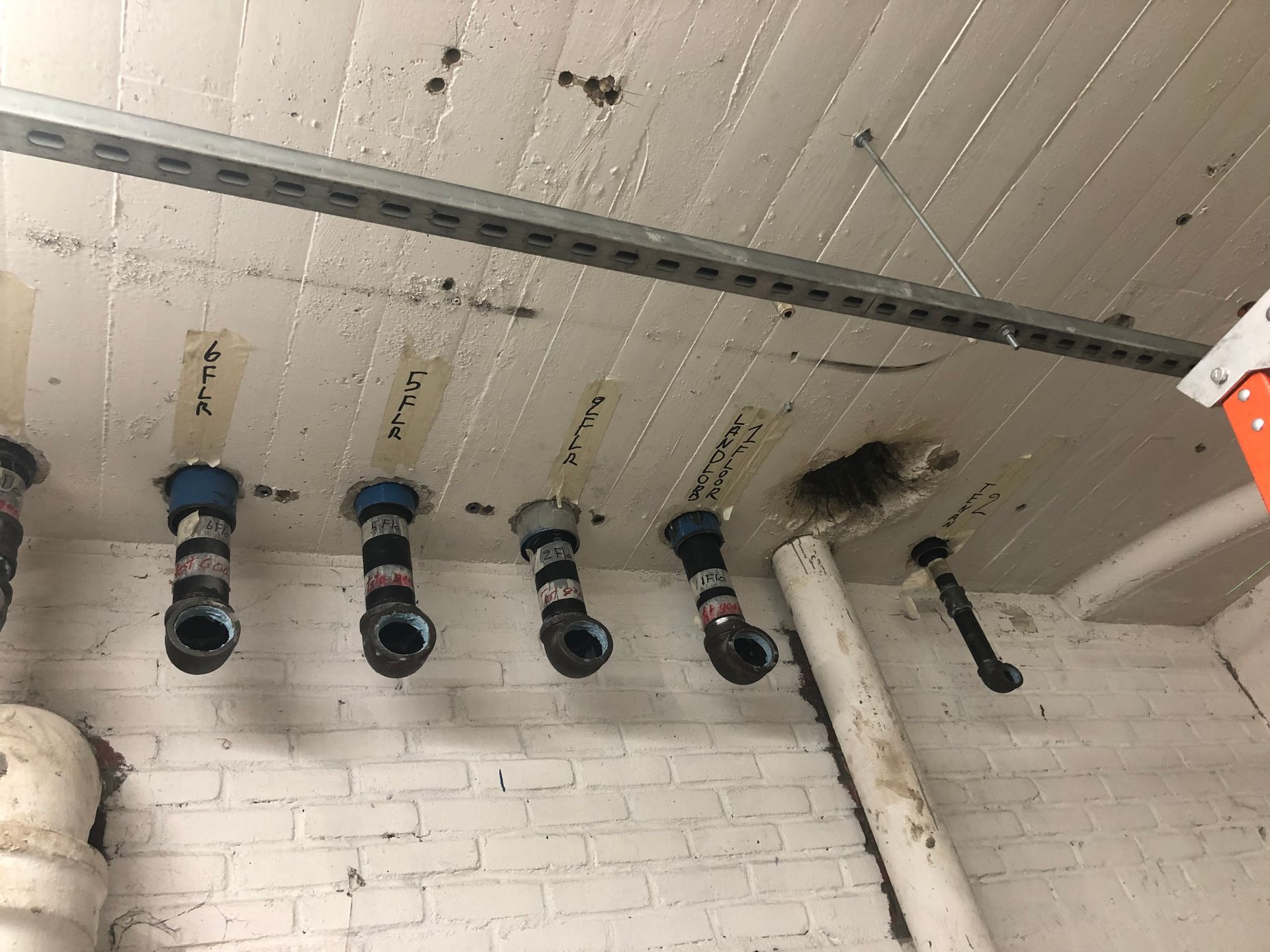 A bunch of pipes are hanging from the ceiling of a building