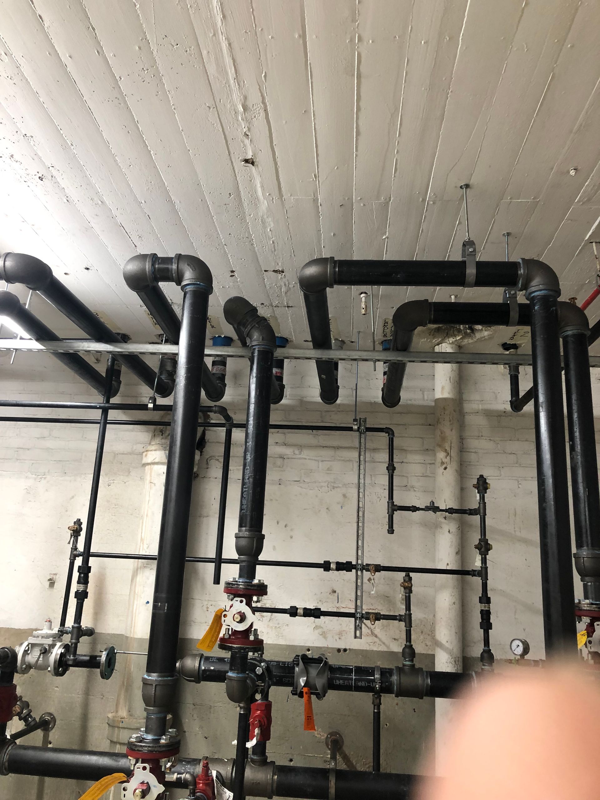 A bunch of pipes are hanging from the ceiling in a room