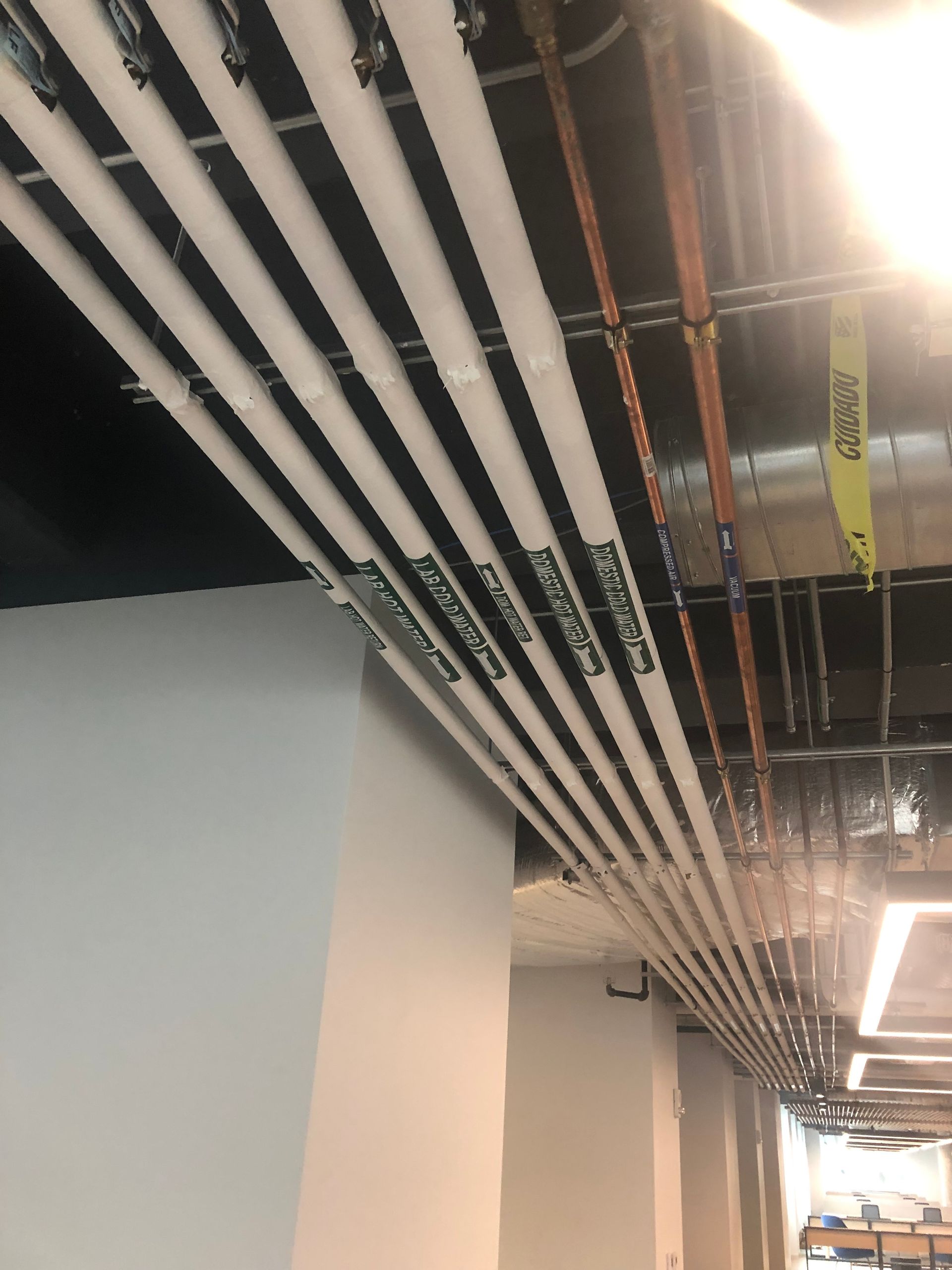 A bunch of pipes are hanging from the ceiling in a building