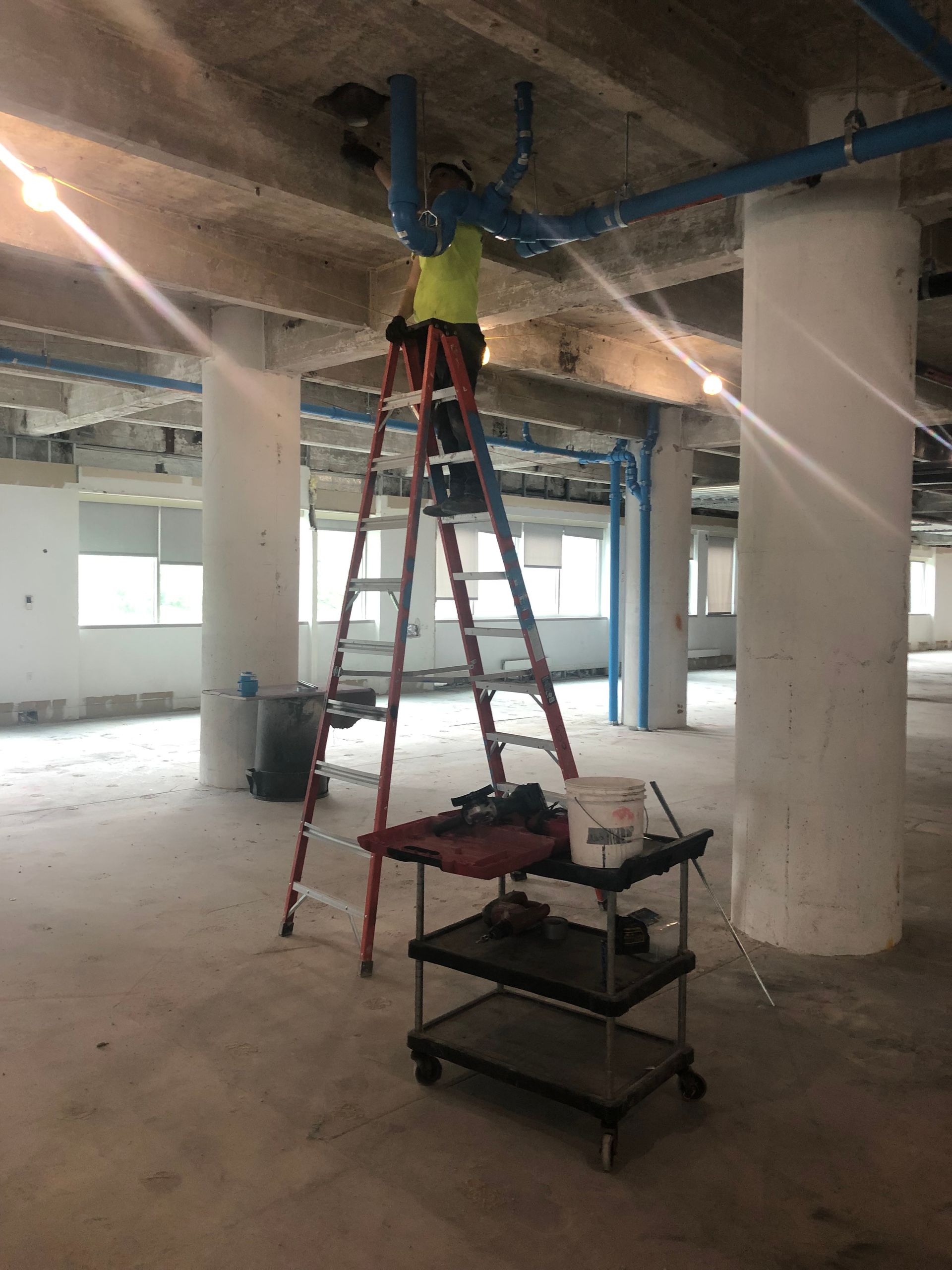 A man is standing on a ladder in an empty room.