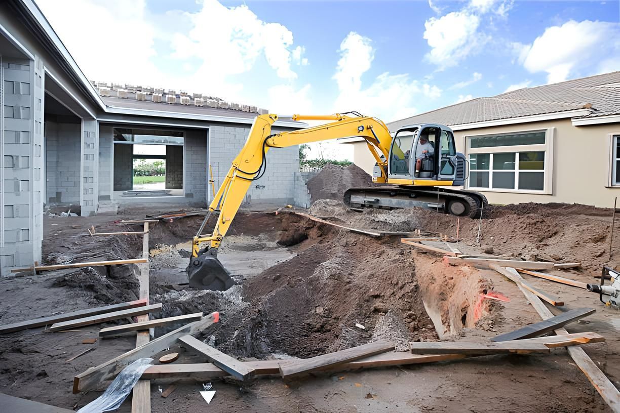 A yellow excavator is digging a hole in front of a house under construction