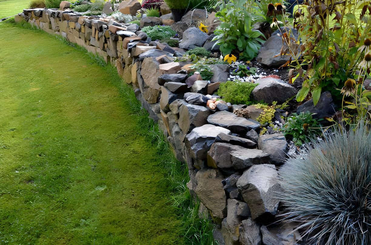 A stone wall surrounds a lush green lawn