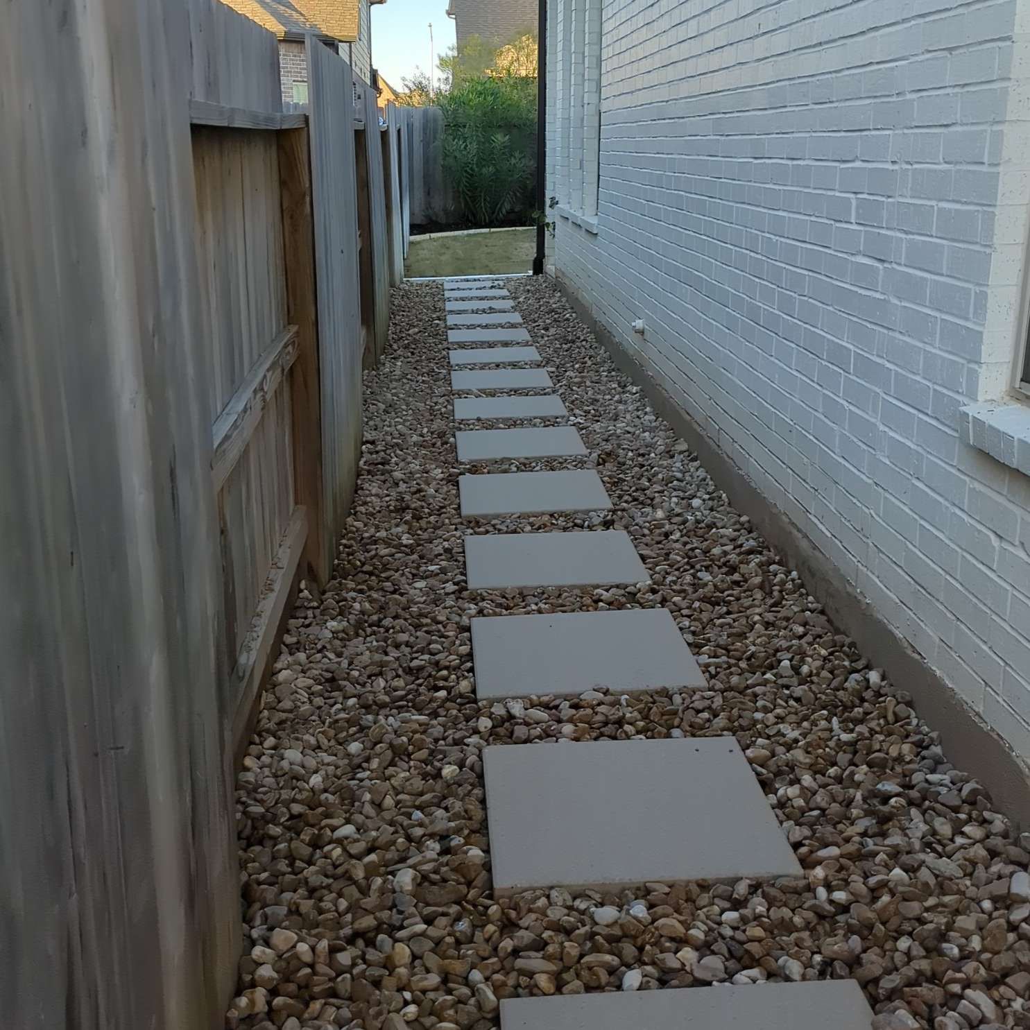 A stone walkway leading to the side of a house